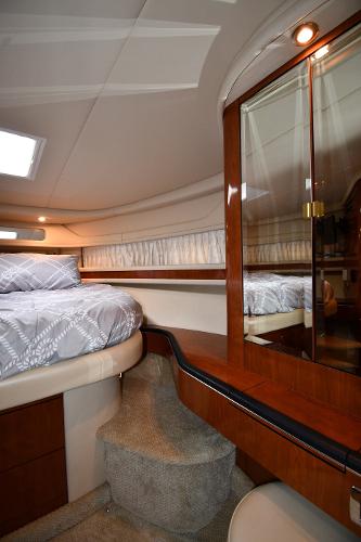 Interior of 2003 Sea Ray 460 Sundancer yacht, featuring a cozy bedroom with elegant wood finishes.