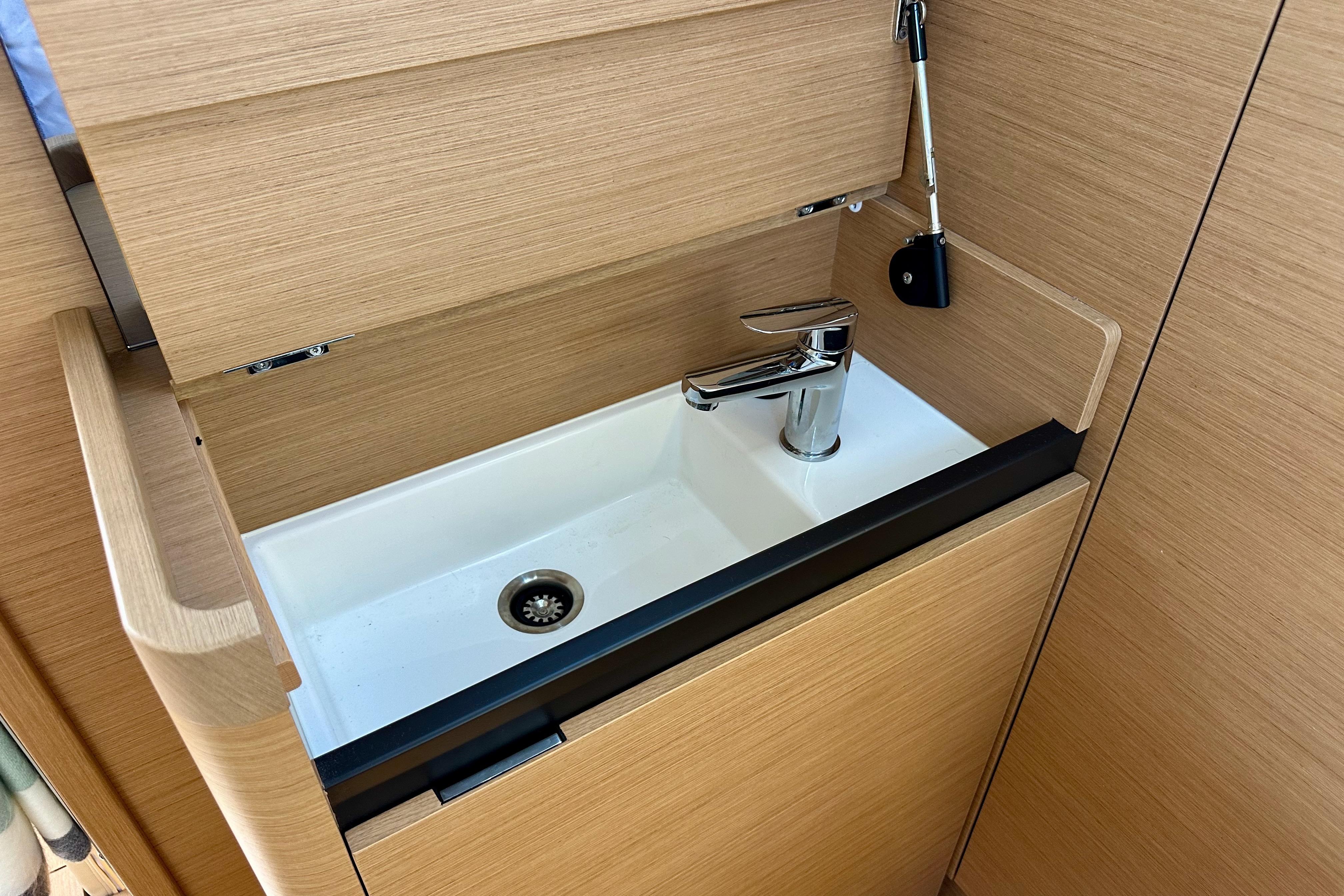2024 Jeanneau Sun Odyssey 410 interior sink with modern faucet and wooden cabinetry.