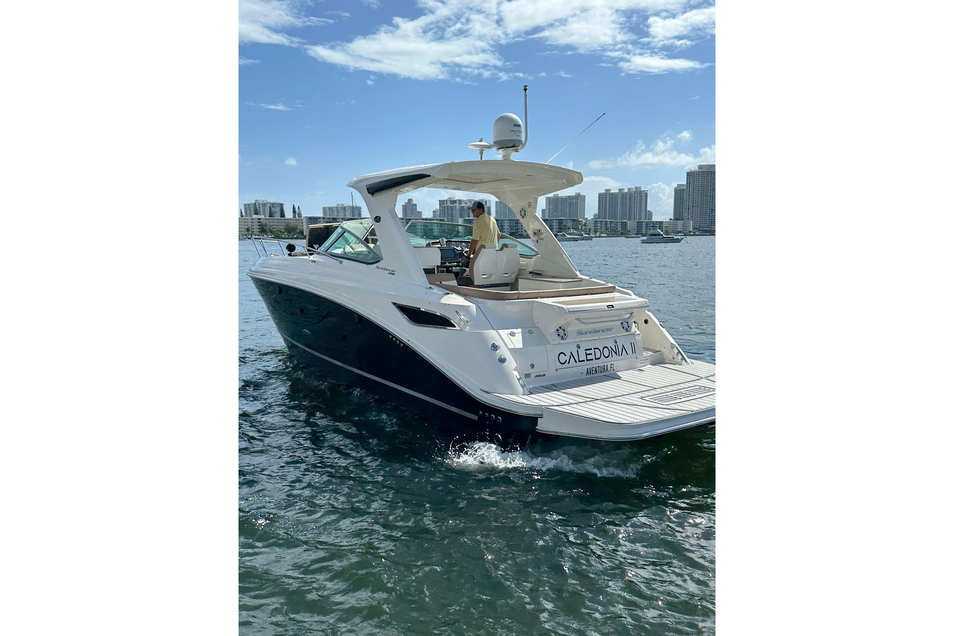 2016 Sea Ray 350 Sundancer yacht cruising on a sunny day with city skyline backdrop.