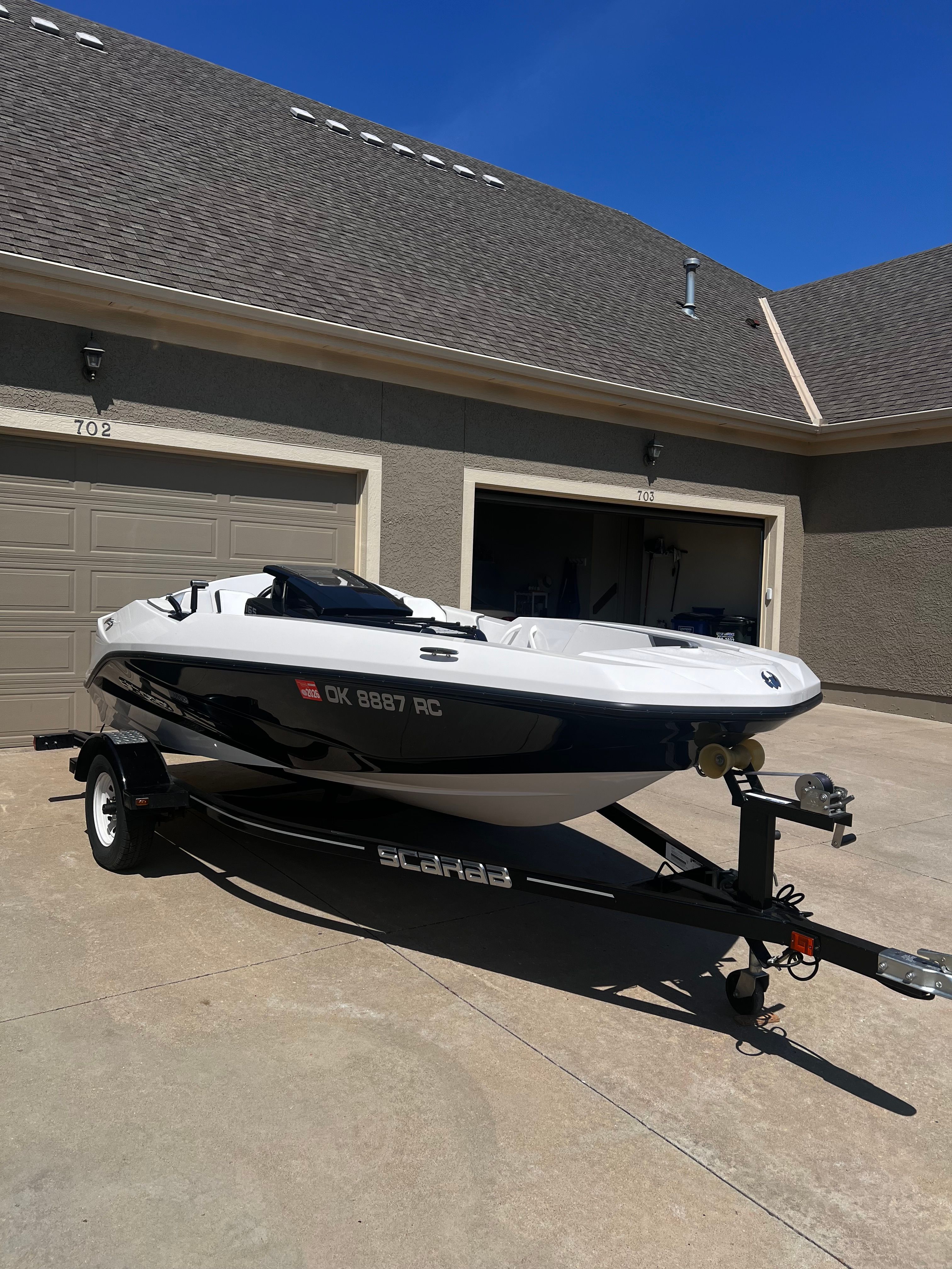 A white 2019 Scarab 165 G boat is on a trailer in a driveway.