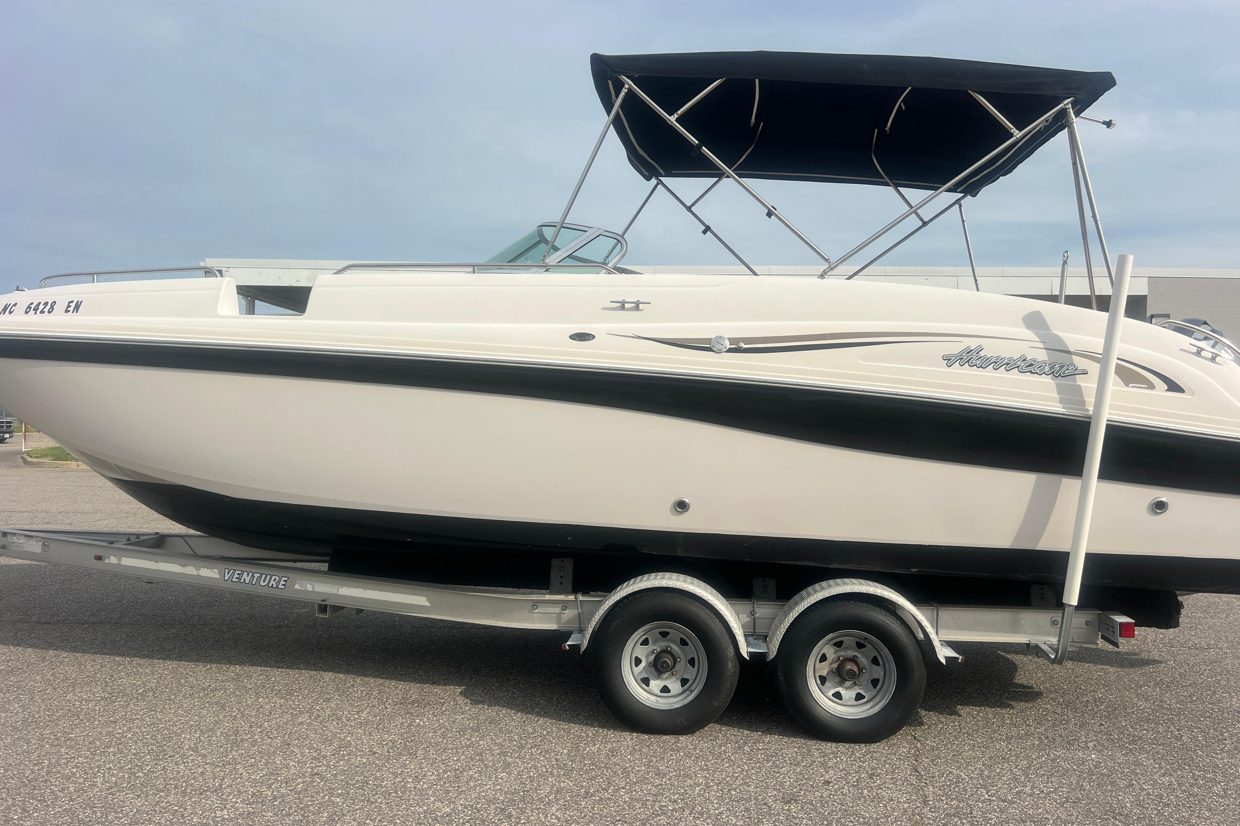 2002 Hurricane SunDeck 260 OB boat on trailer, featuring a sleek design and canopy.