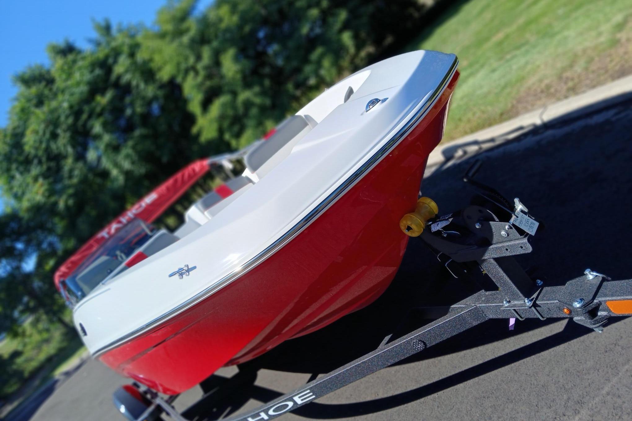 2026 Tahoe T16 boat on trailer, red and white design, parked outdoors.