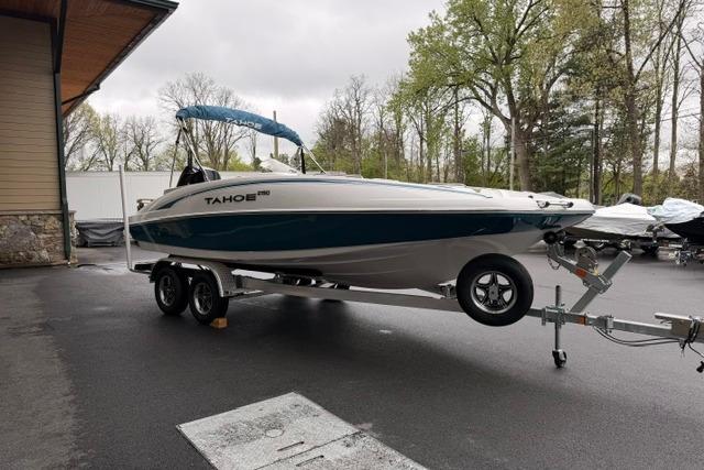 2026 Tahoe 2150 boat on trailer, parked outdoors near trees and building.