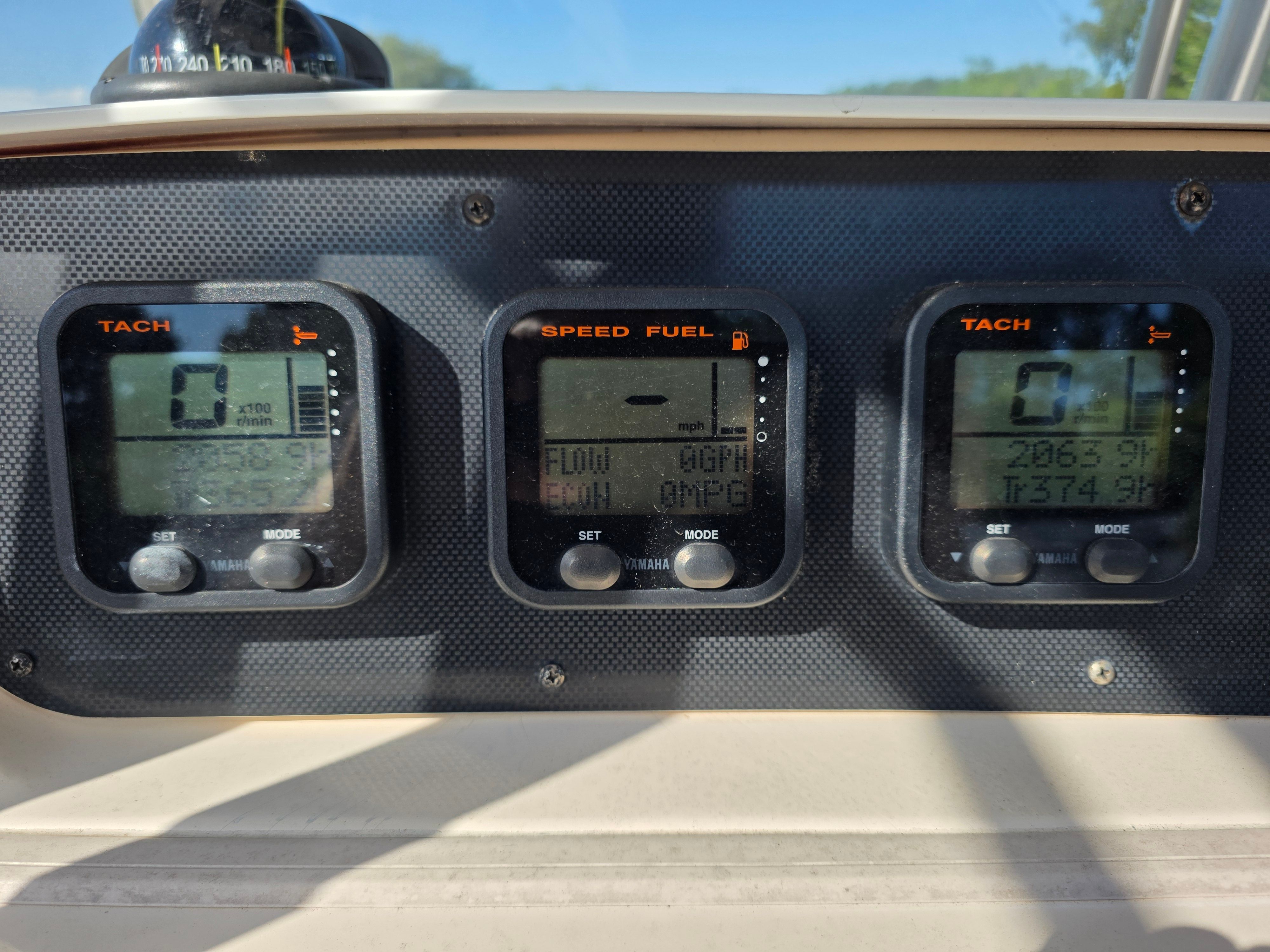 Three digital gauges on a boat panel display tachometers and fuel consumption.