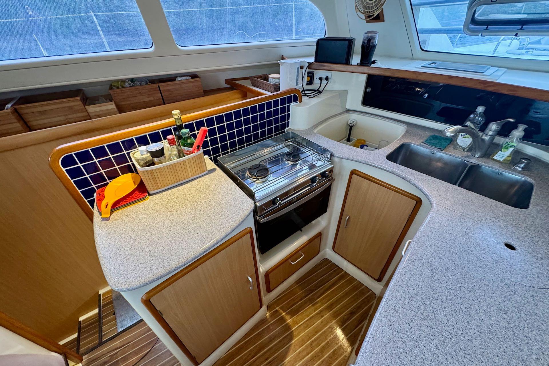 Compact kitchen in a 2004 Leopard 42 yacht with stove, sink, and storage.