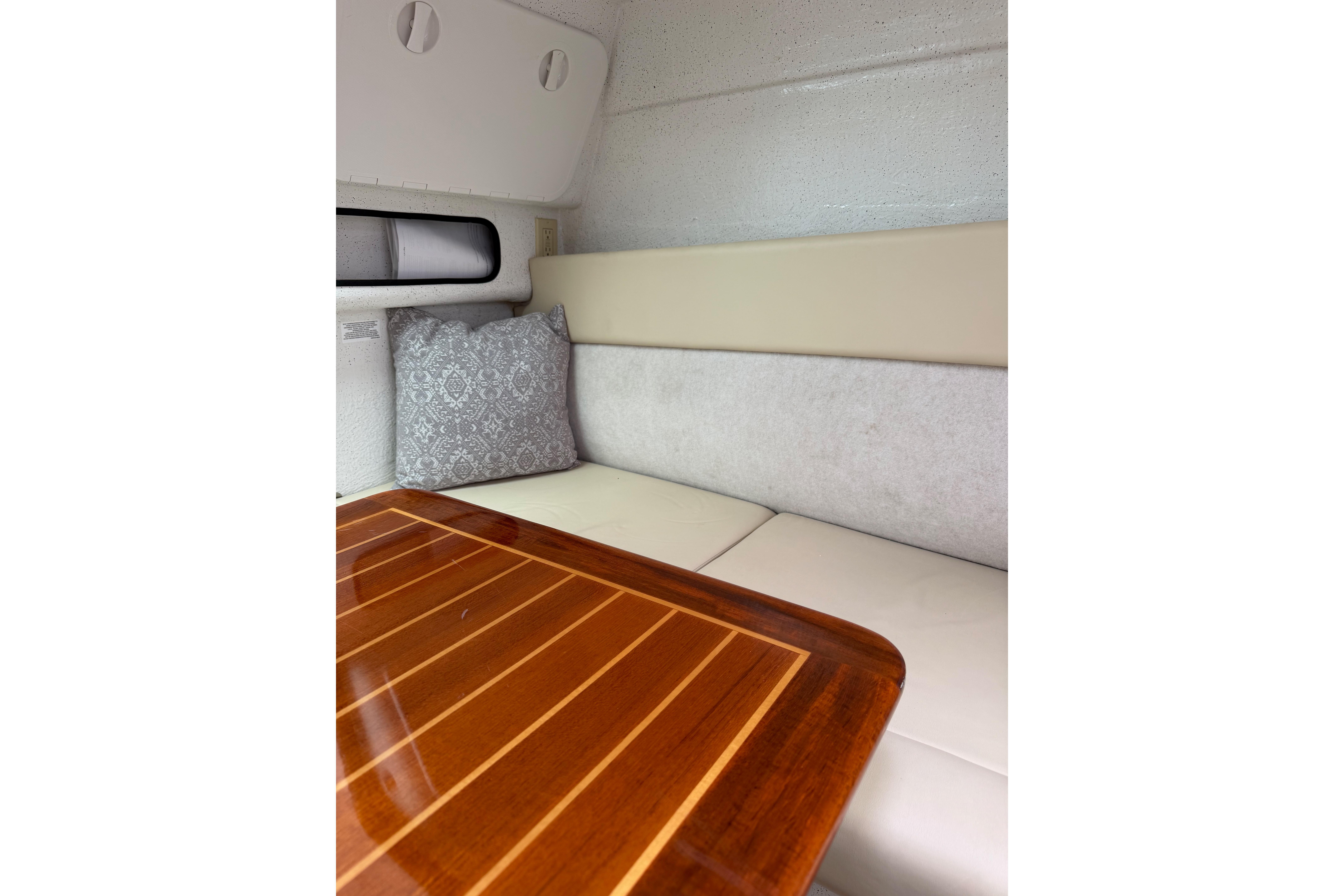 Interior of 2016 Protector Targa 30 boat with cushioned seating and wooden table.