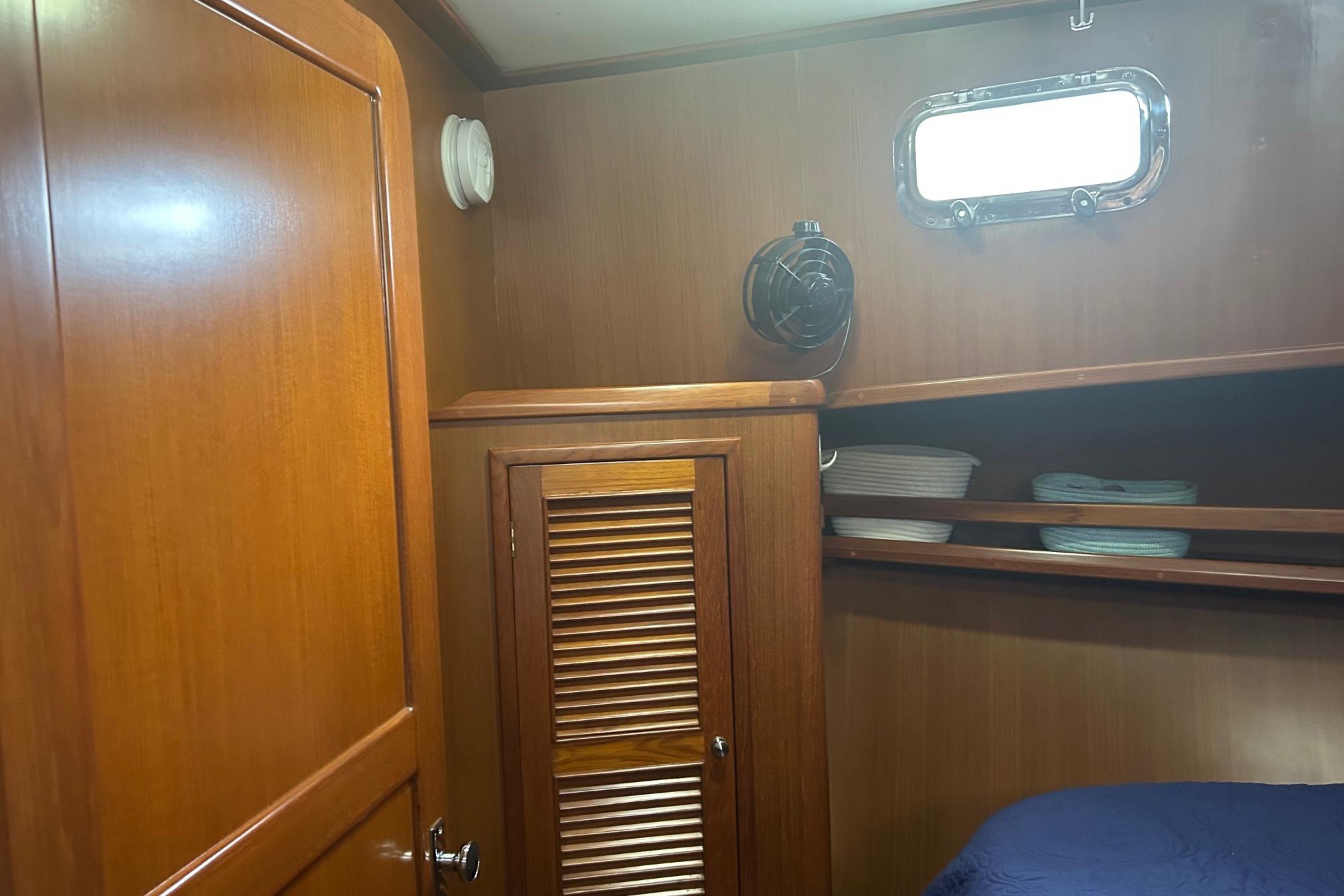 2006 Mariner Orient cabin interior with wooden paneling, shelves, and porthole window.