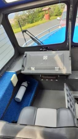 Interior of a boat with blue seats and a control panel.