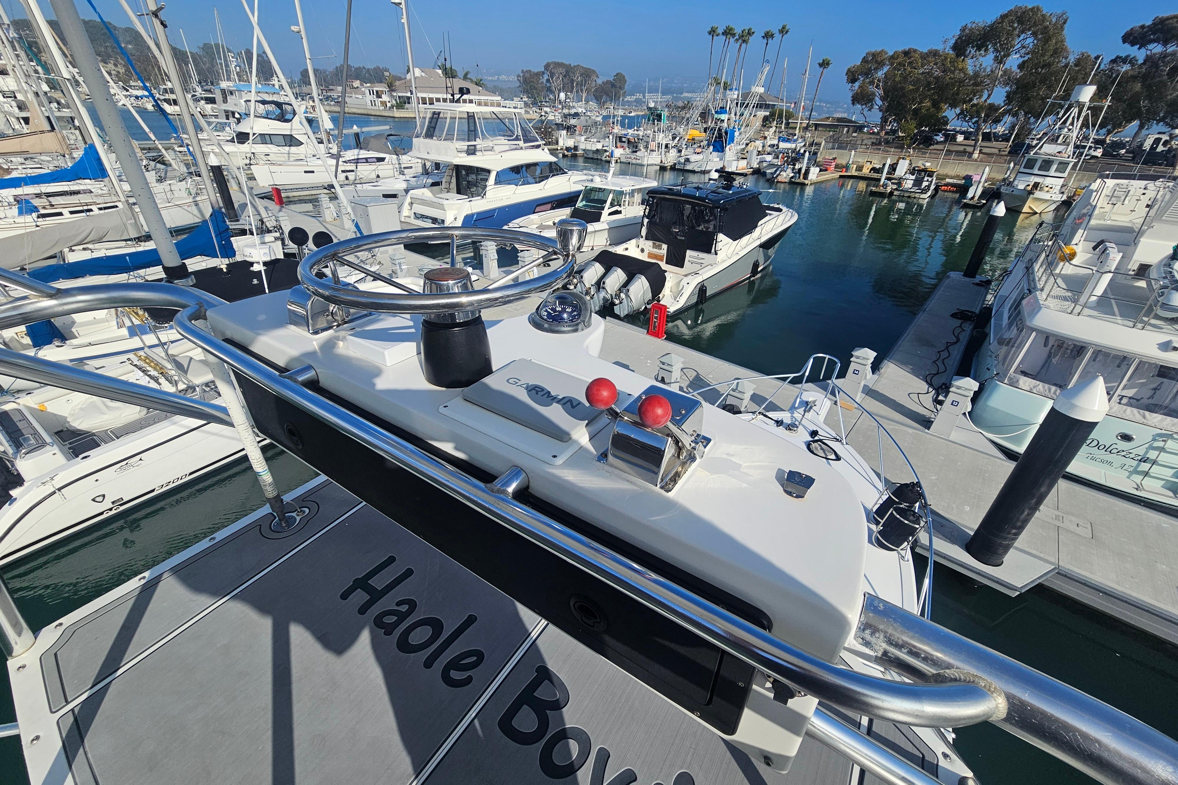 Helm of 2003 Topaz 32 Express yacht in marina, surrounded by boats.