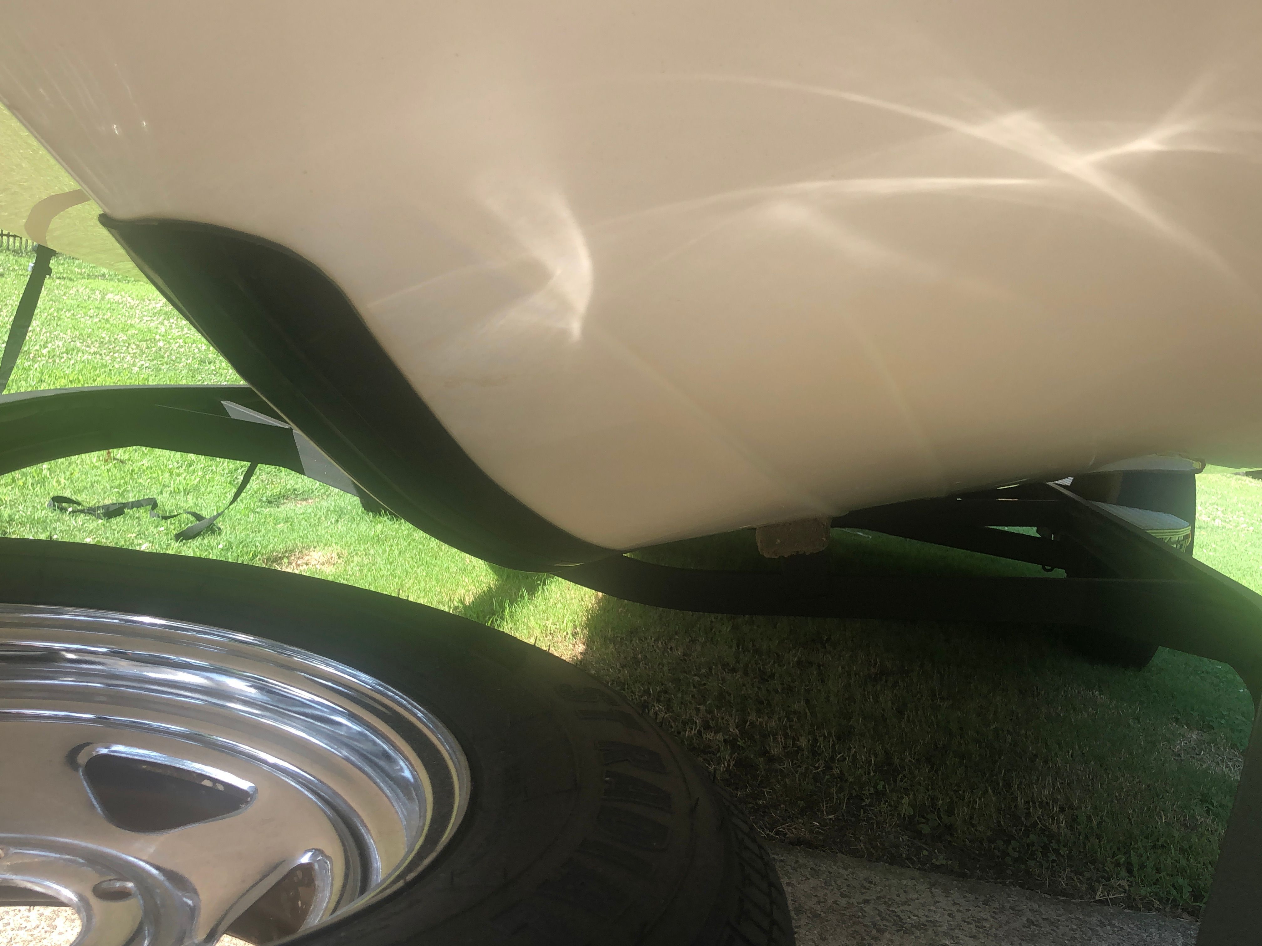 Close-up of a boat hull on a trailer, with a shiny wheel in the foreground.