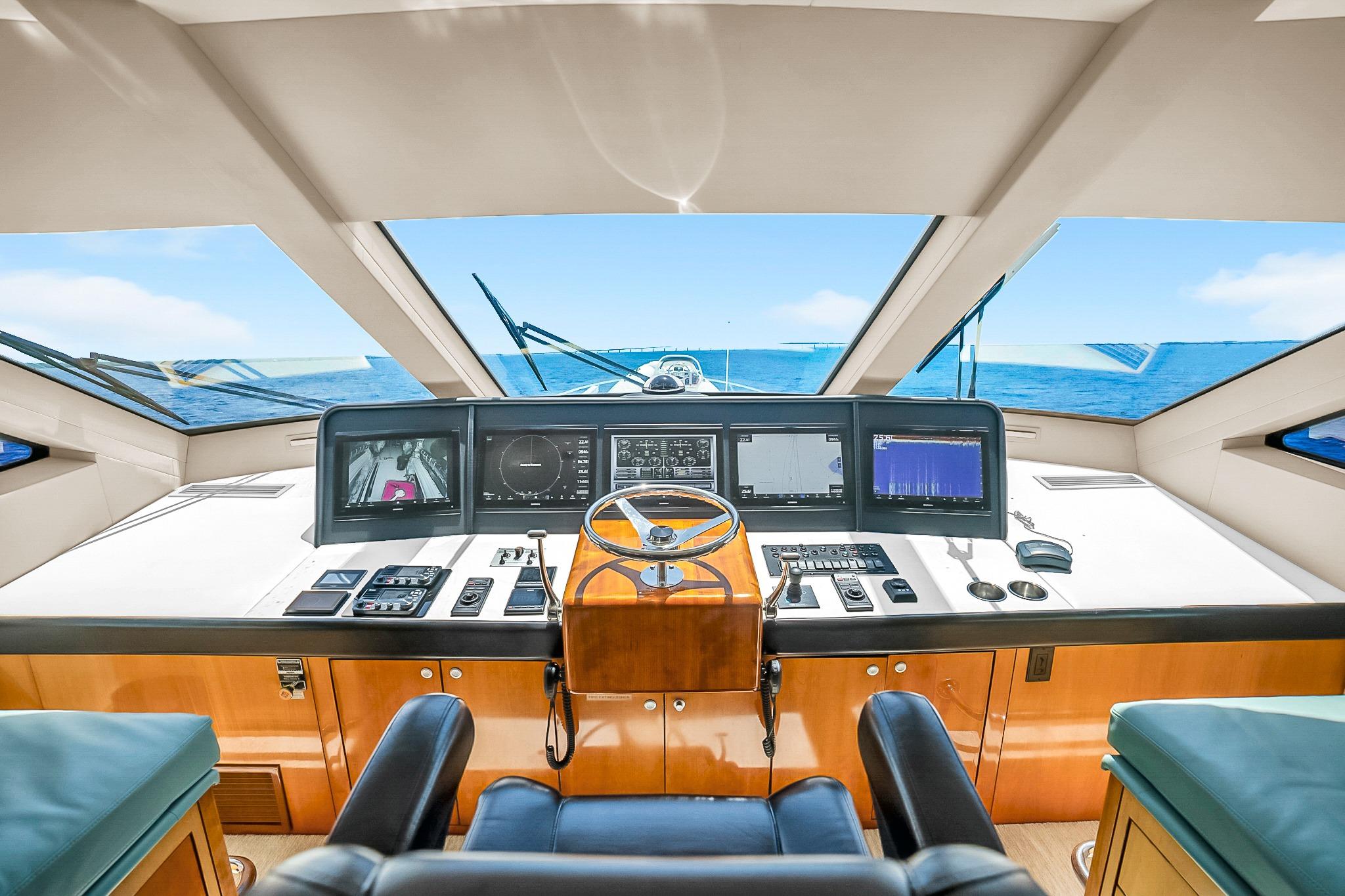Helm of 2008 Hatteras 77 Convertible yacht with modern navigation equipment and ocean view.