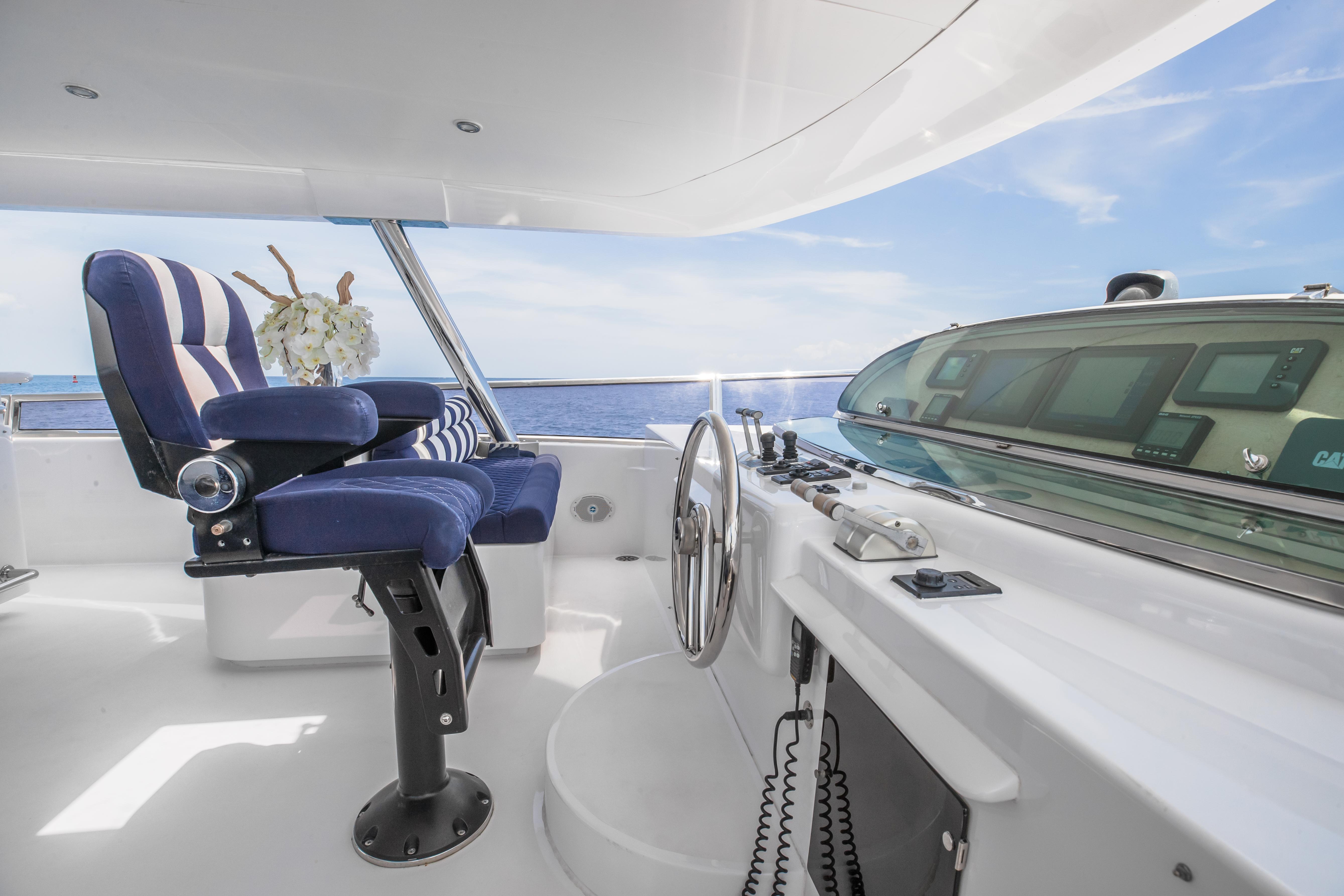 Helm station of 2005 Horizon 94 Motoryacht with blue captain's chair and ocean view.