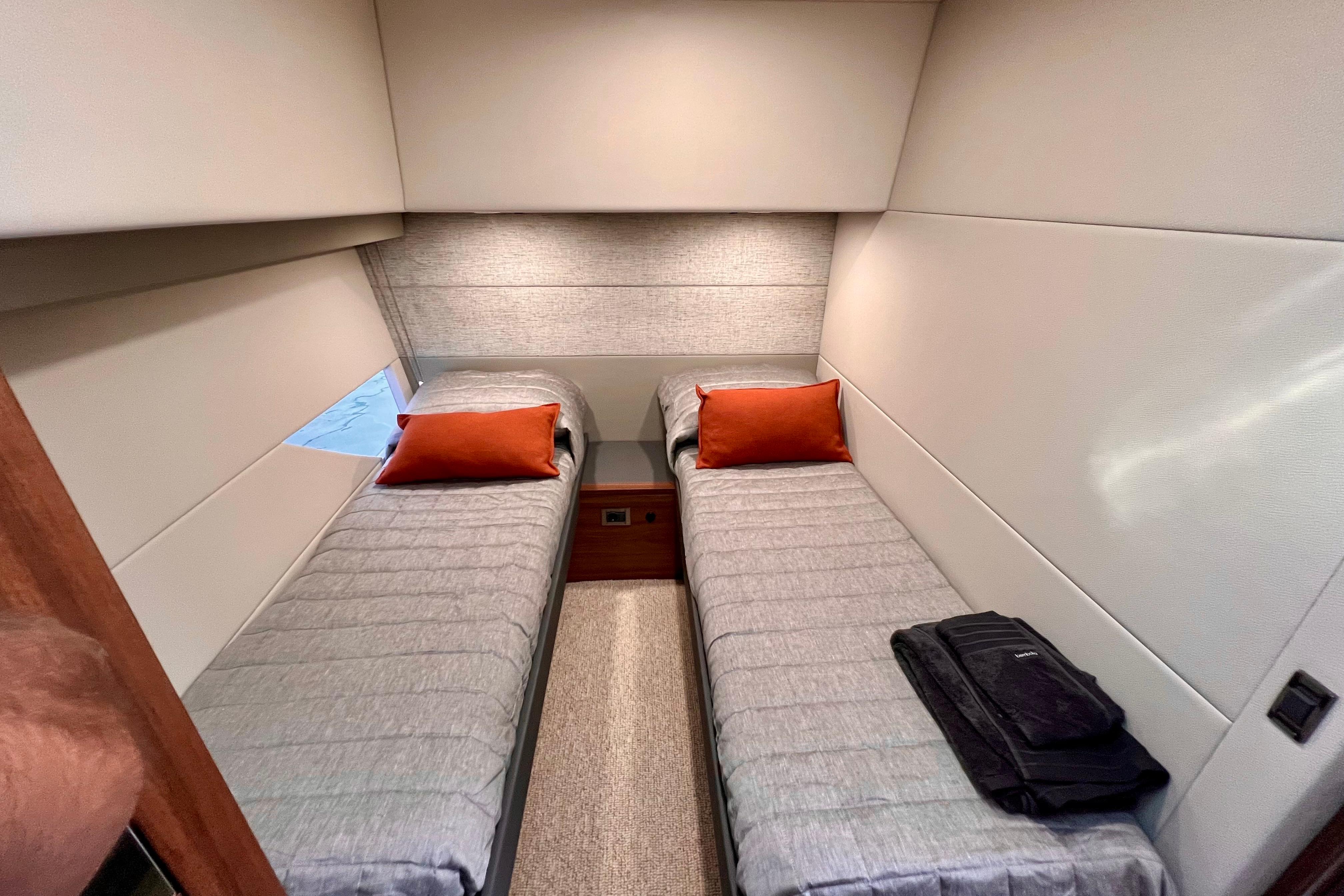 2023 Maritimo M600 yacht cabin with twin beds, gray bedding, and orange pillows.
