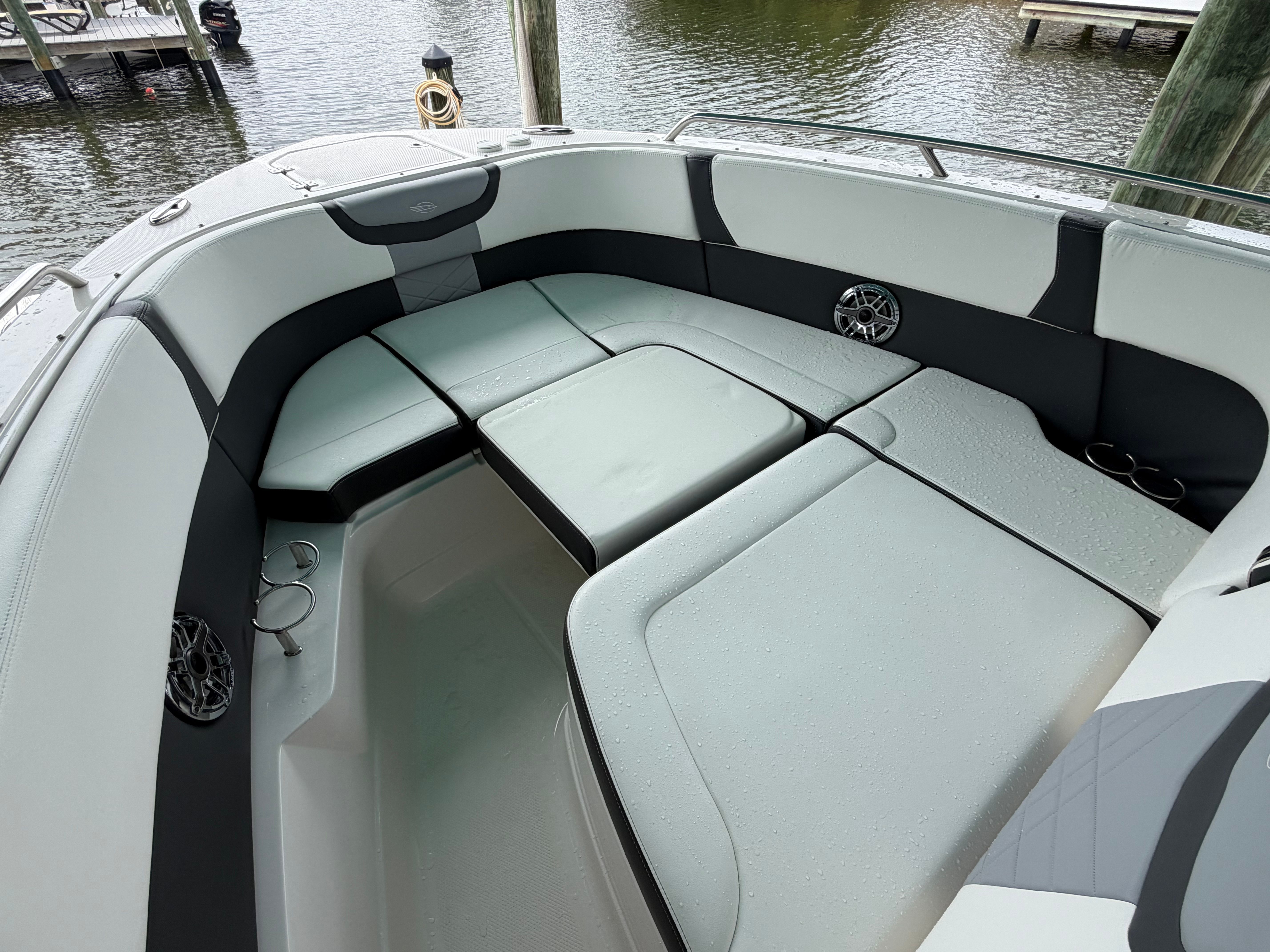 A sleek boat with gray and black upholstery, docked at a calm pier.