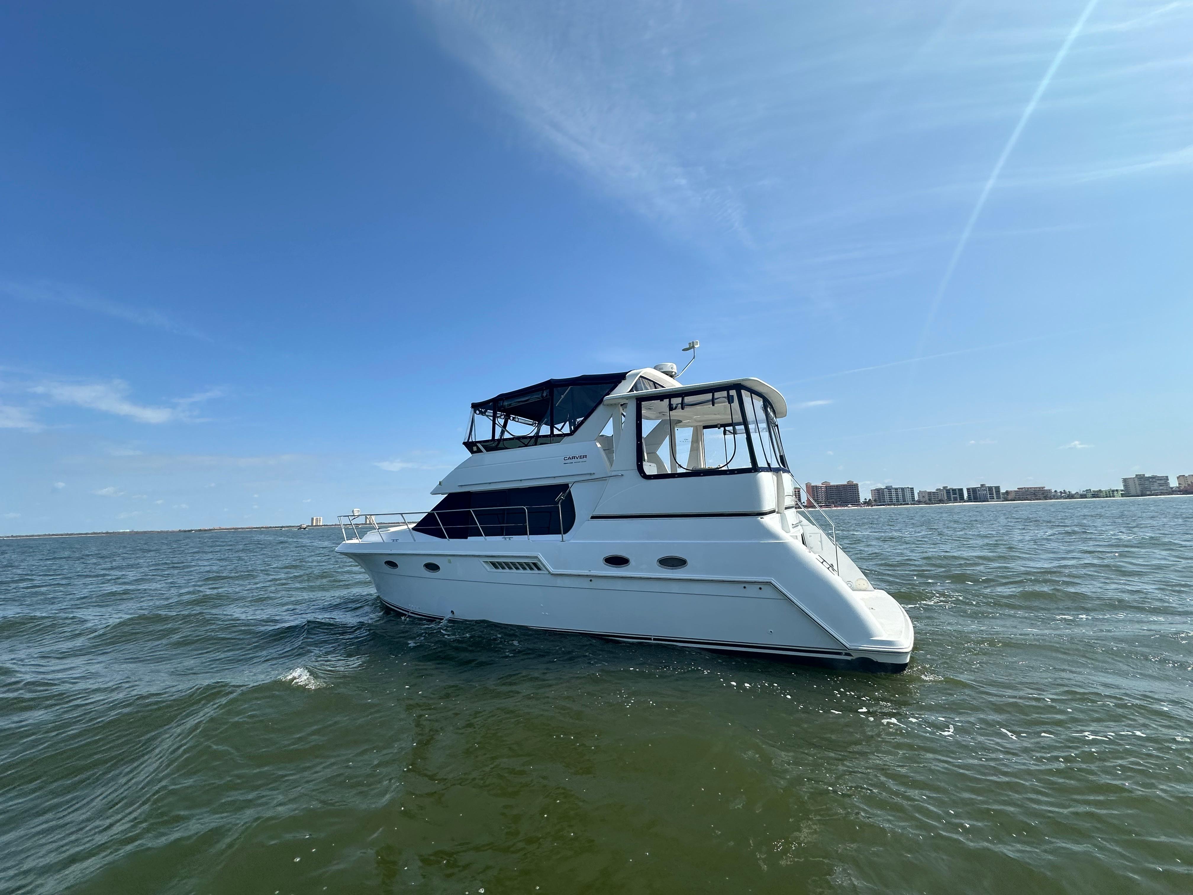 2000 Carver 406 Motor Yacht cruising on open water under a clear blue sky.