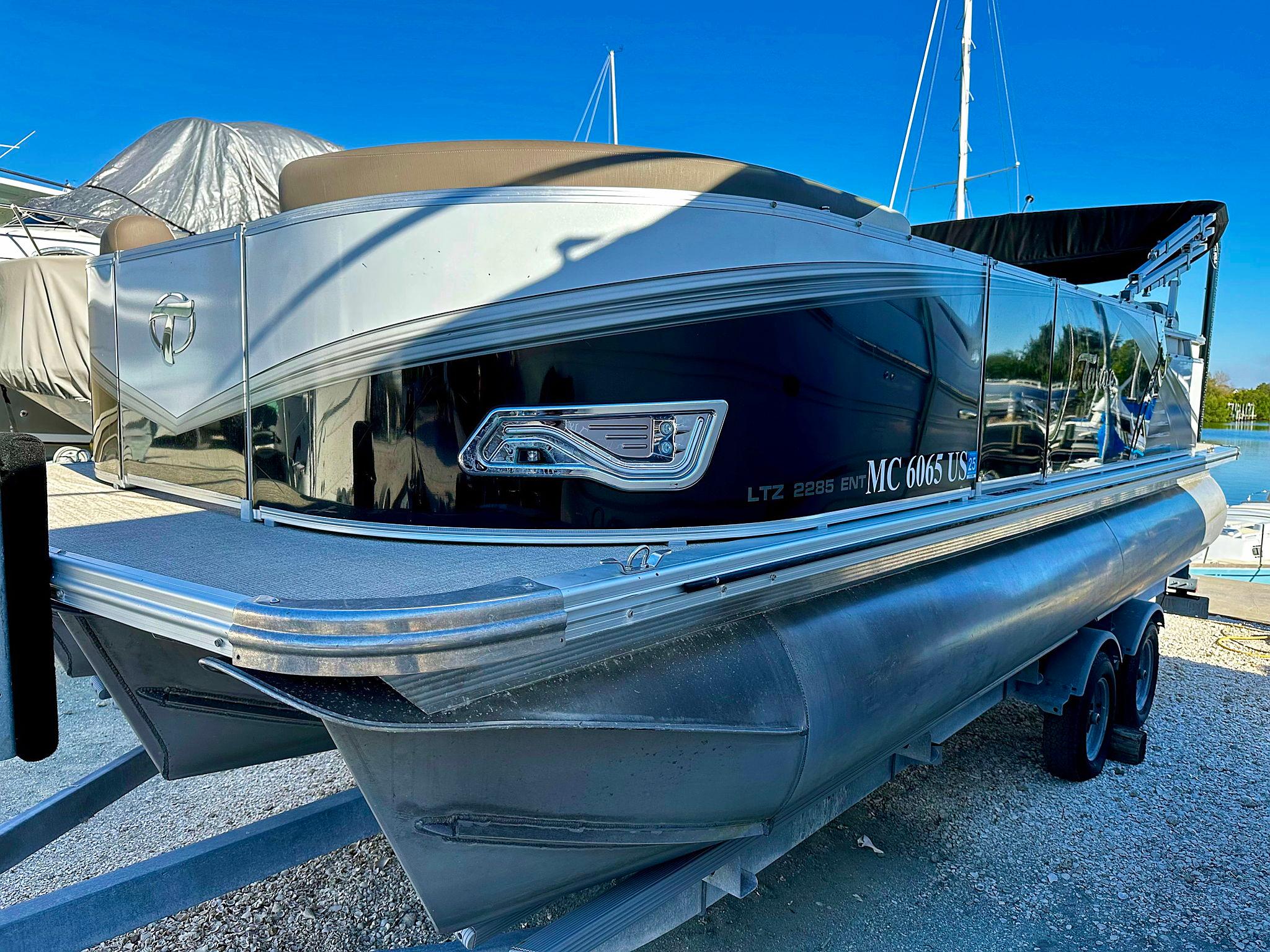 2022 Tahoe LTZ 2285 ENT Tritoon boat on trailer, sleek design, docked outdoors.
