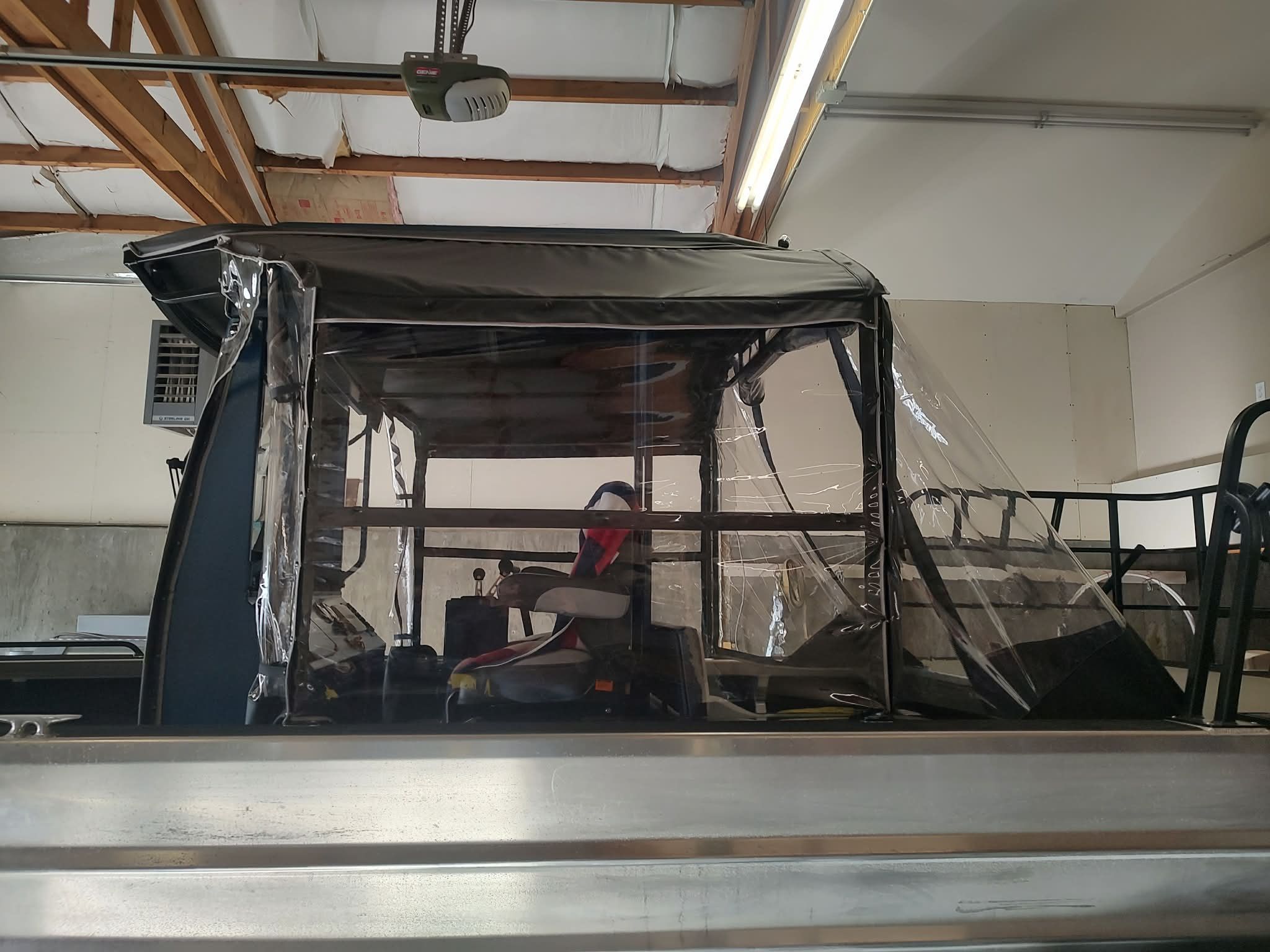 A Custom Weld 23' sled t-top boat in a garage with transparent side panels.