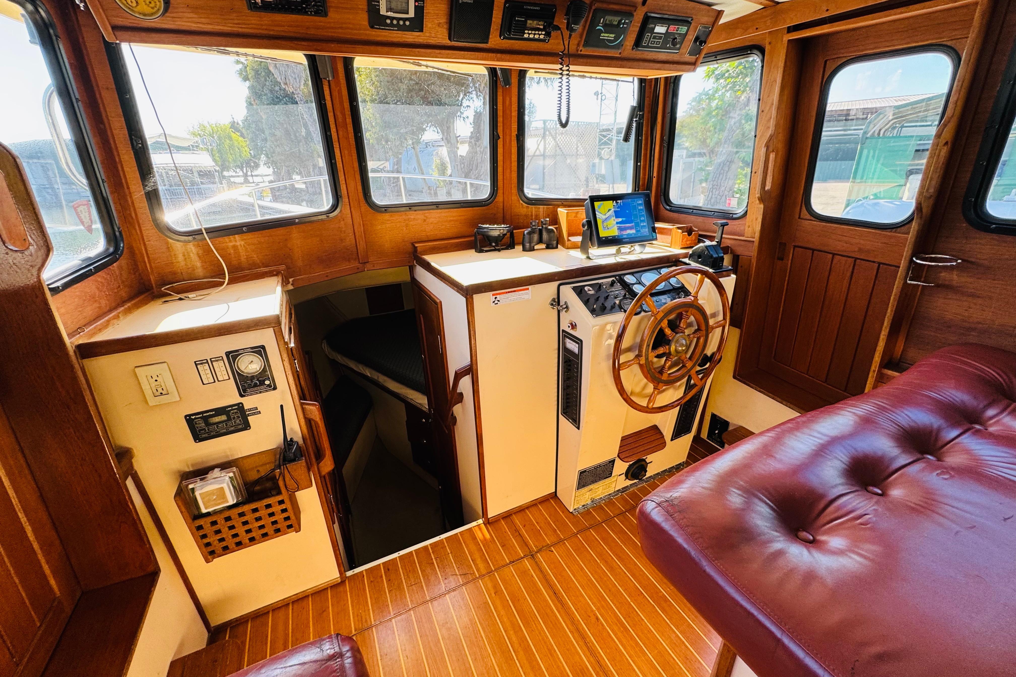 1996 Nordic Tug 32 interior with wooden helm, navigation equipment, and cozy seating.