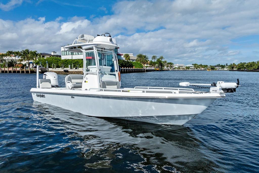 2023 Everglades 243 Center Console boat on calm water, with scenic waterfront background.