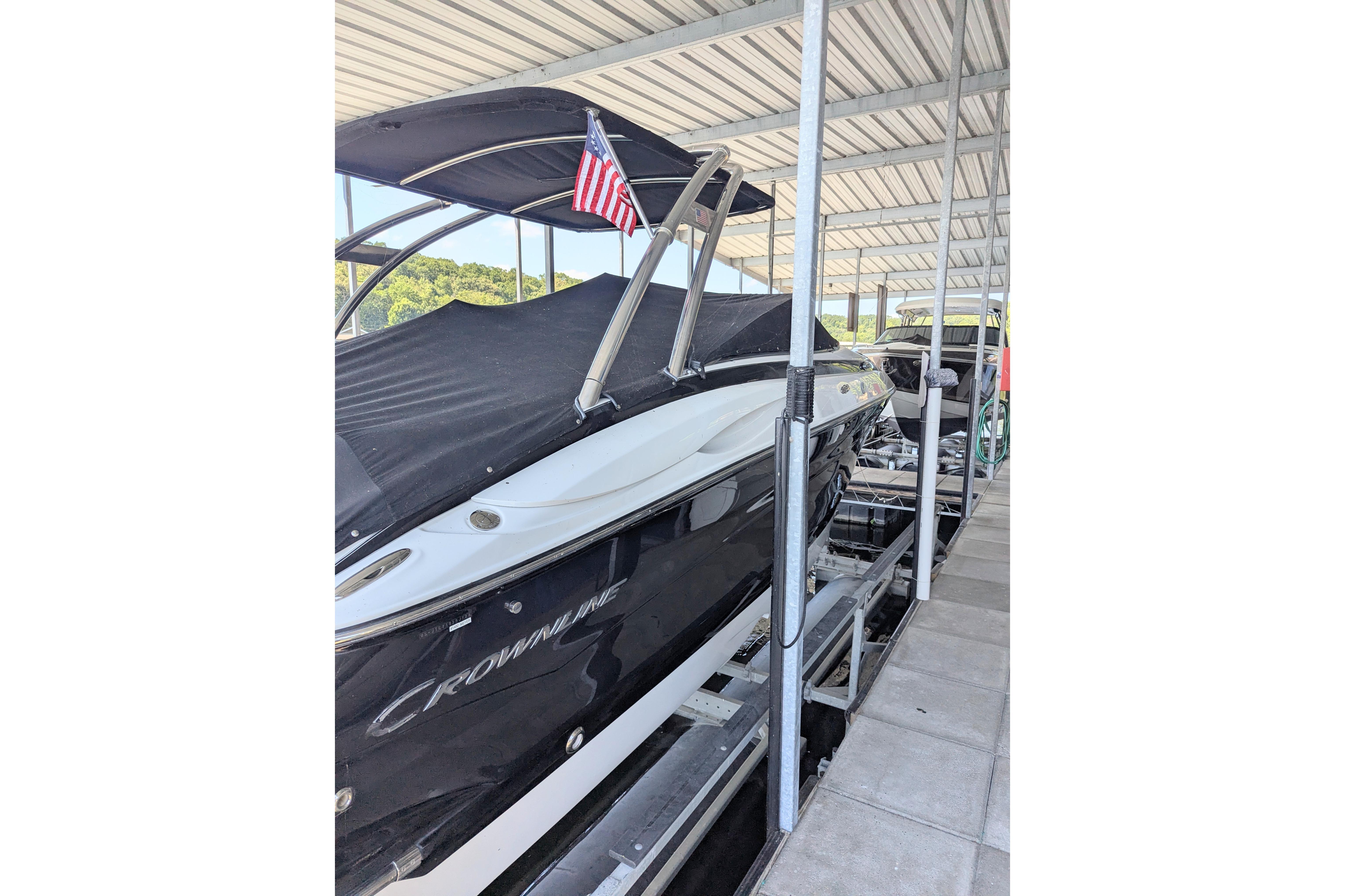 2008 Crownline 300 LS boat docked under a covered marina with an American flag.