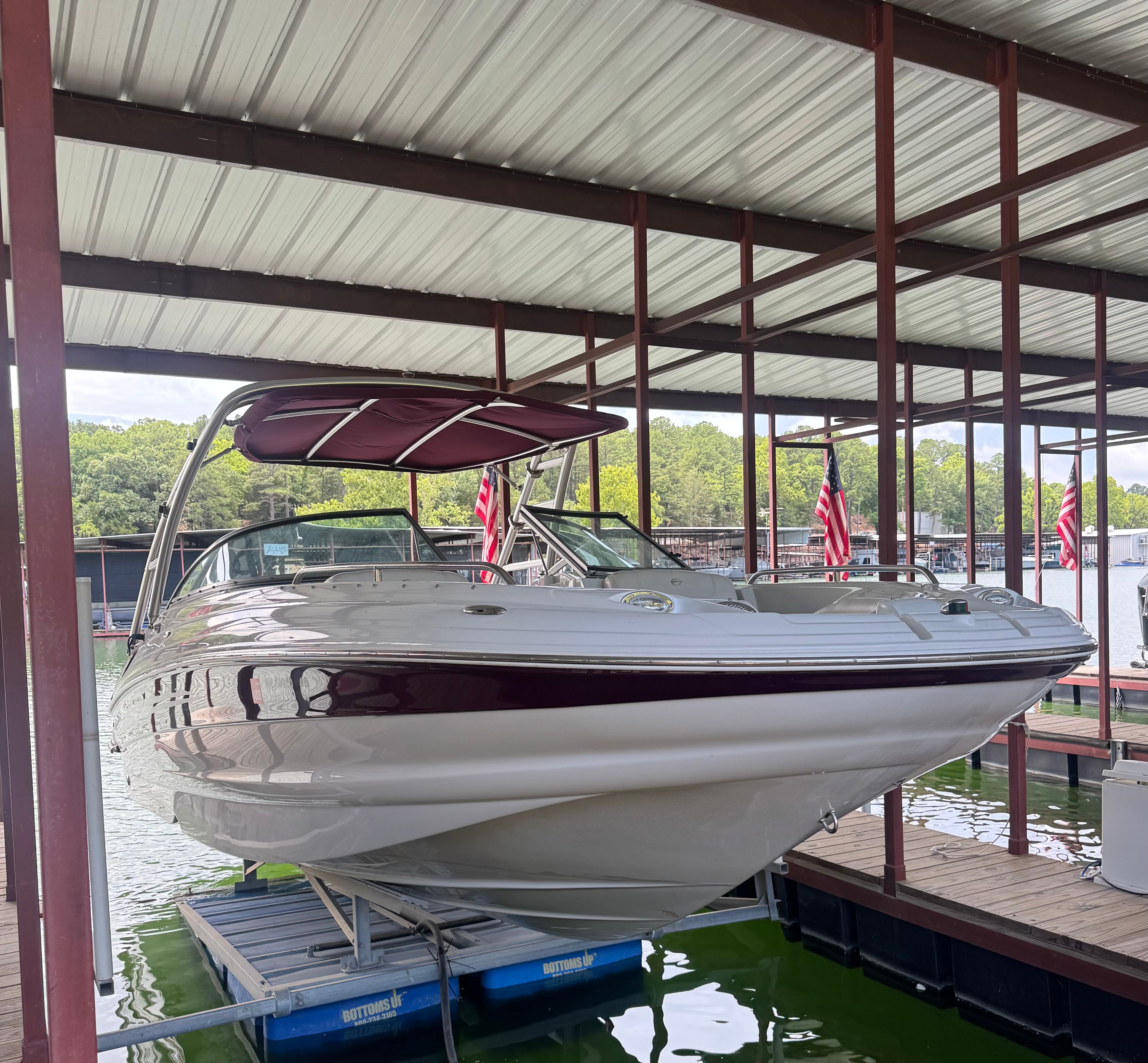 A 2008 Crownline 252EX boat is docked under a covered area. It features a sunshade and is surrounded by water.