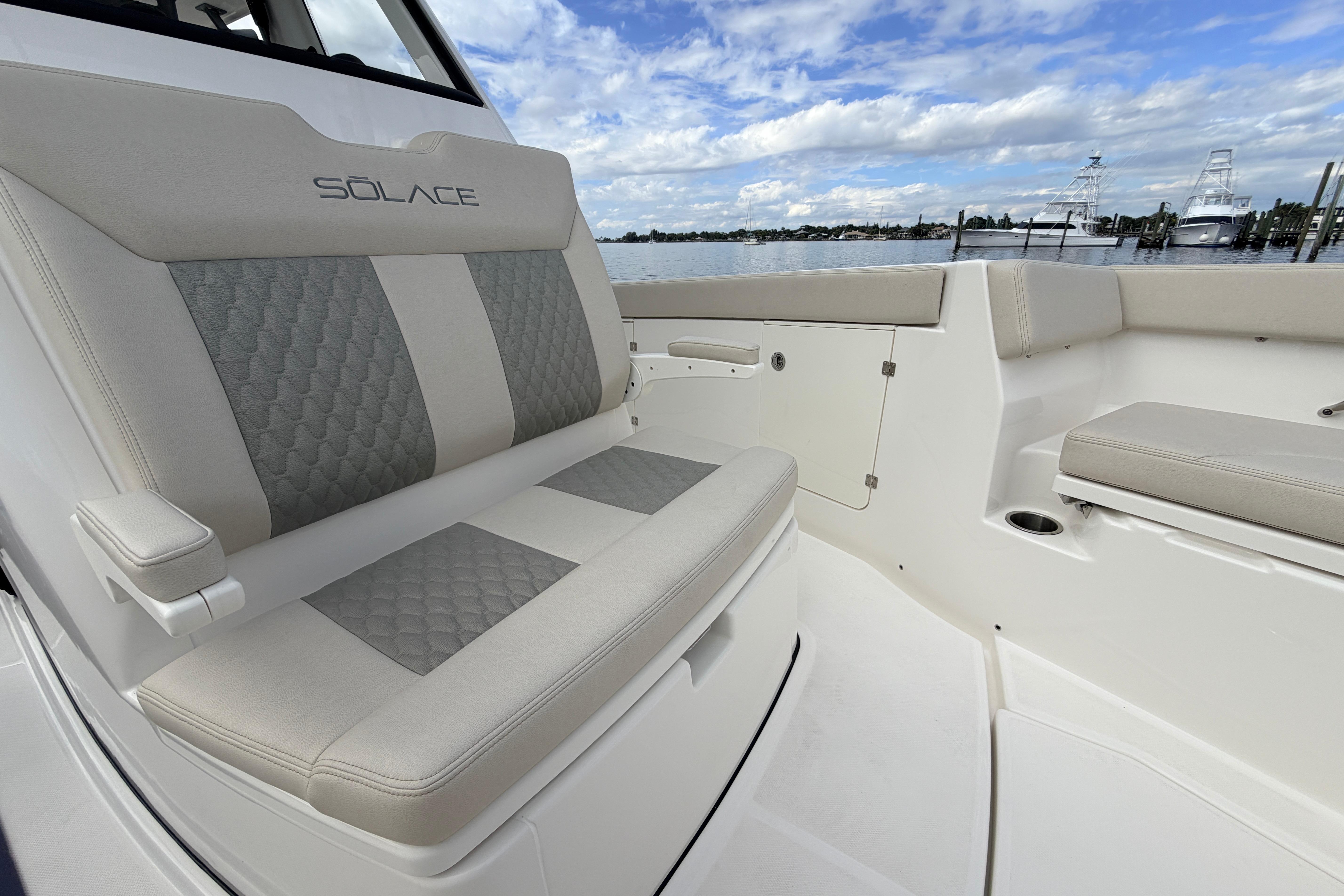 Luxurious seating on 2026 Solace 30 CS boat with scenic waterfront view.