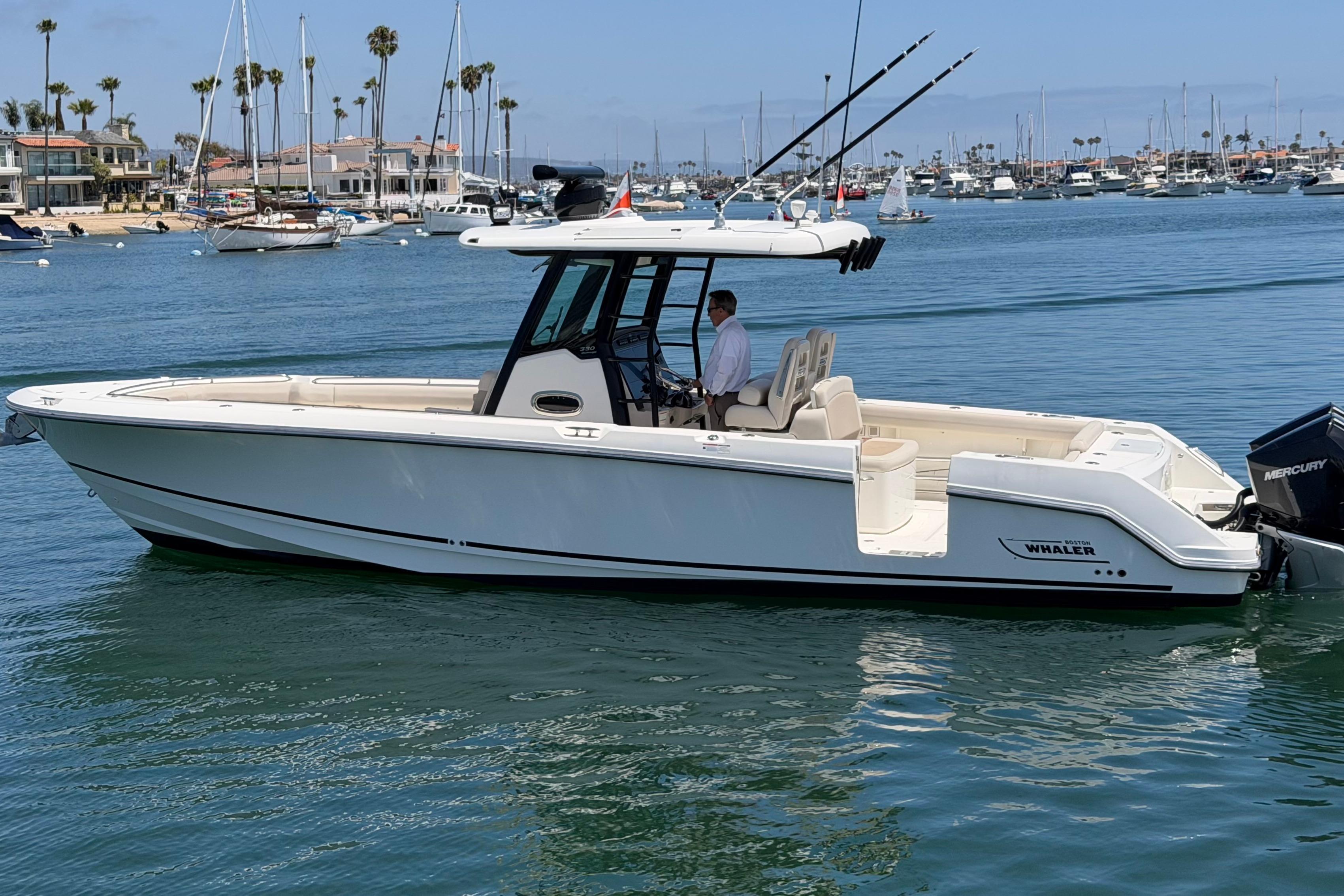 2021 Boston Whaler 330 Outrage boat cruising in a marina with scenic background.