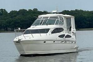 2005 Cruisers Yachts 405 Express Motoryacht on calm water, surrounded by trees.