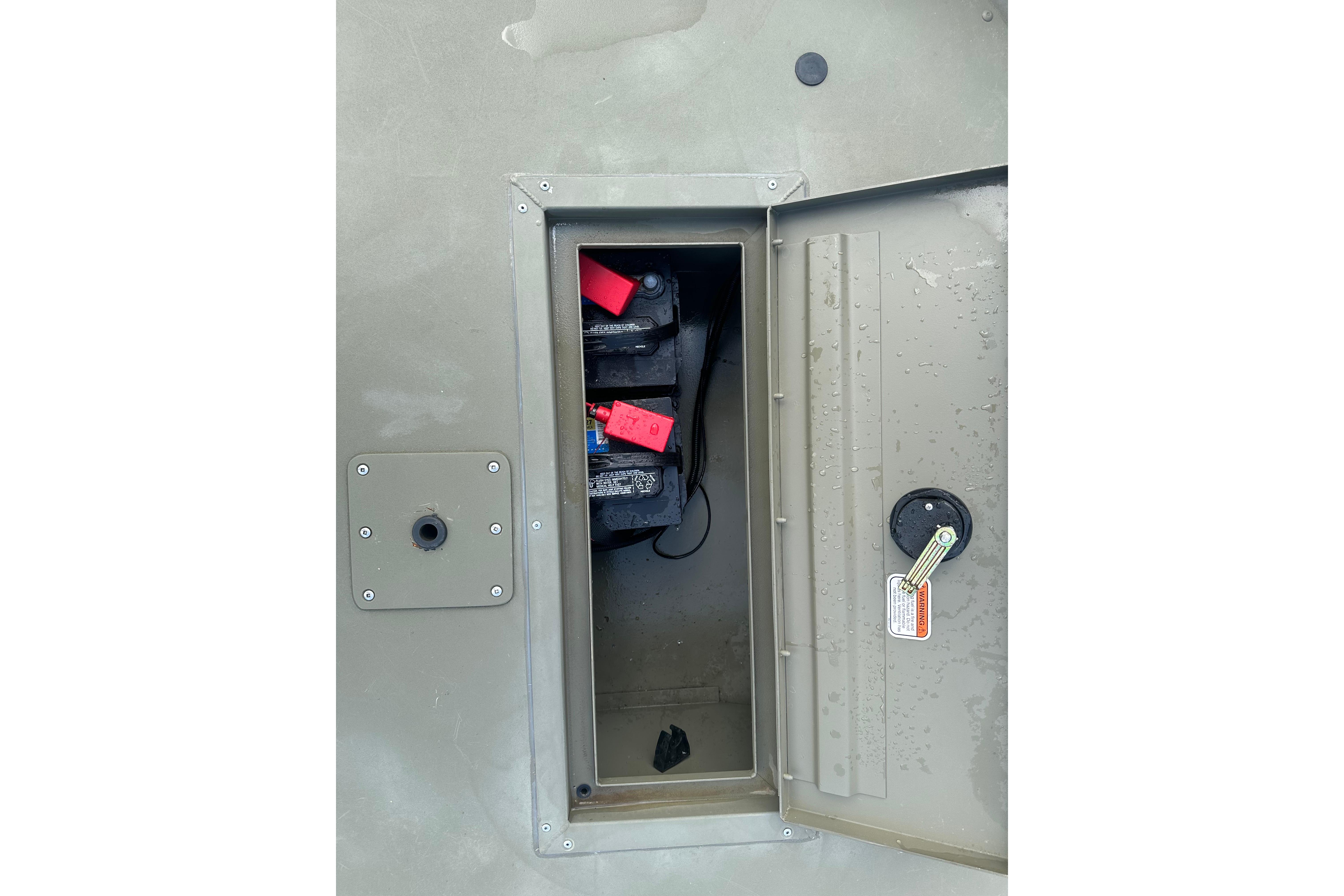 2024 Tracker Grizzly 1648 SC boat battery compartment with open hatch and visible wiring.