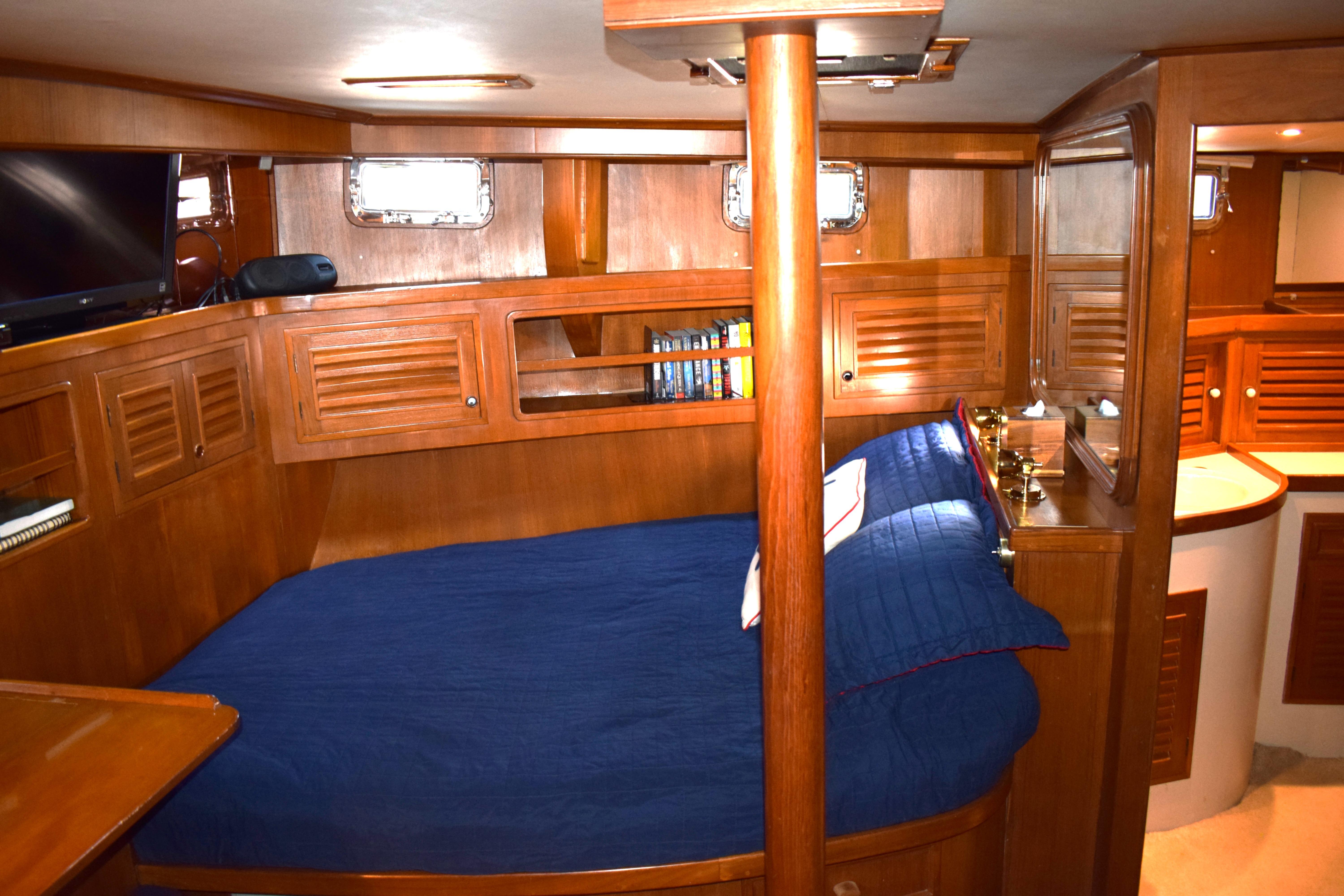 Cozy cabin interior of 1980 Cheoy Lee 52 Motorsailer with wooden furnishings and blue bedding.