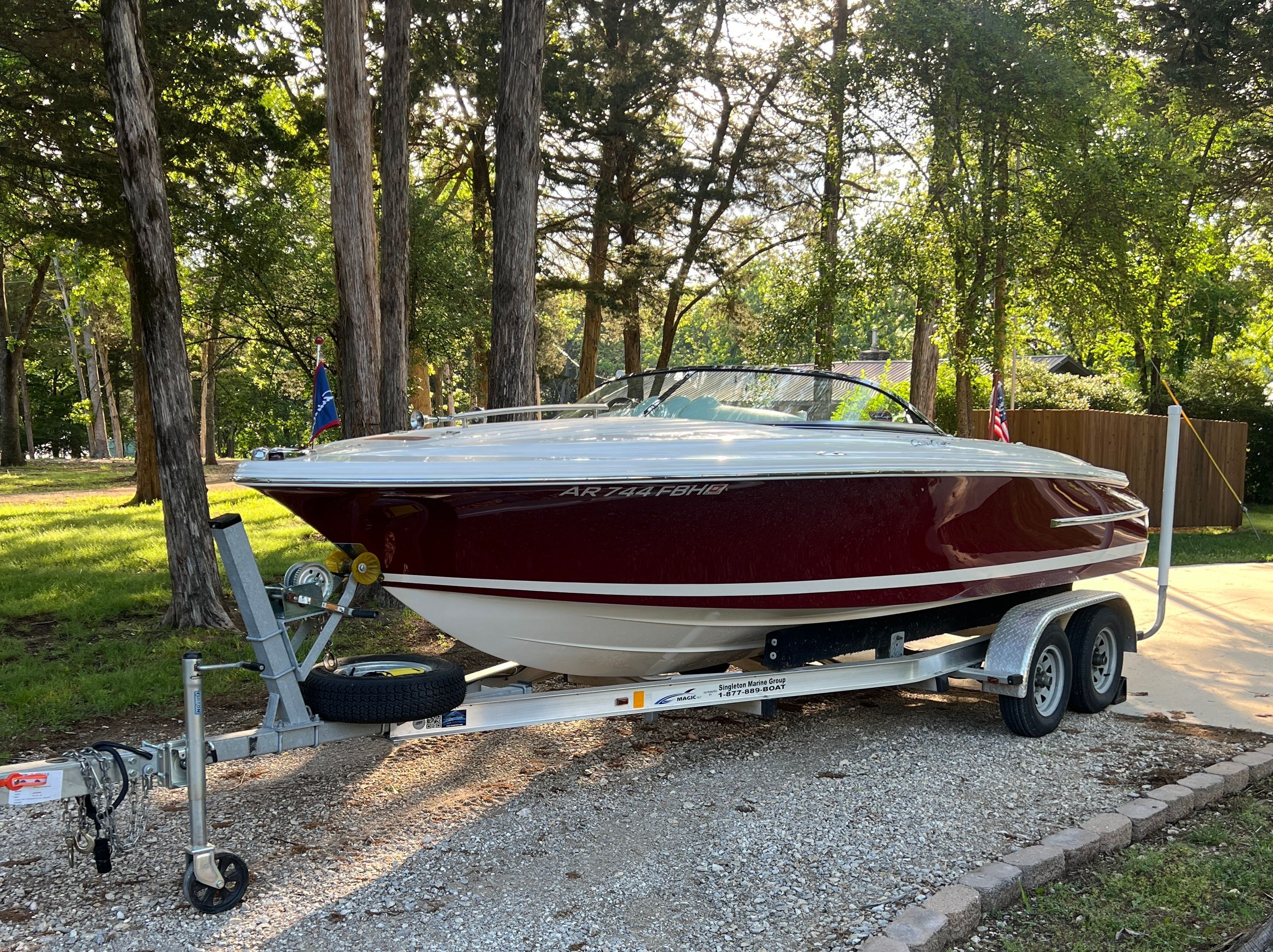 A 2006 Chris-Craft Speedster 20 on a trailer in a wooded area.