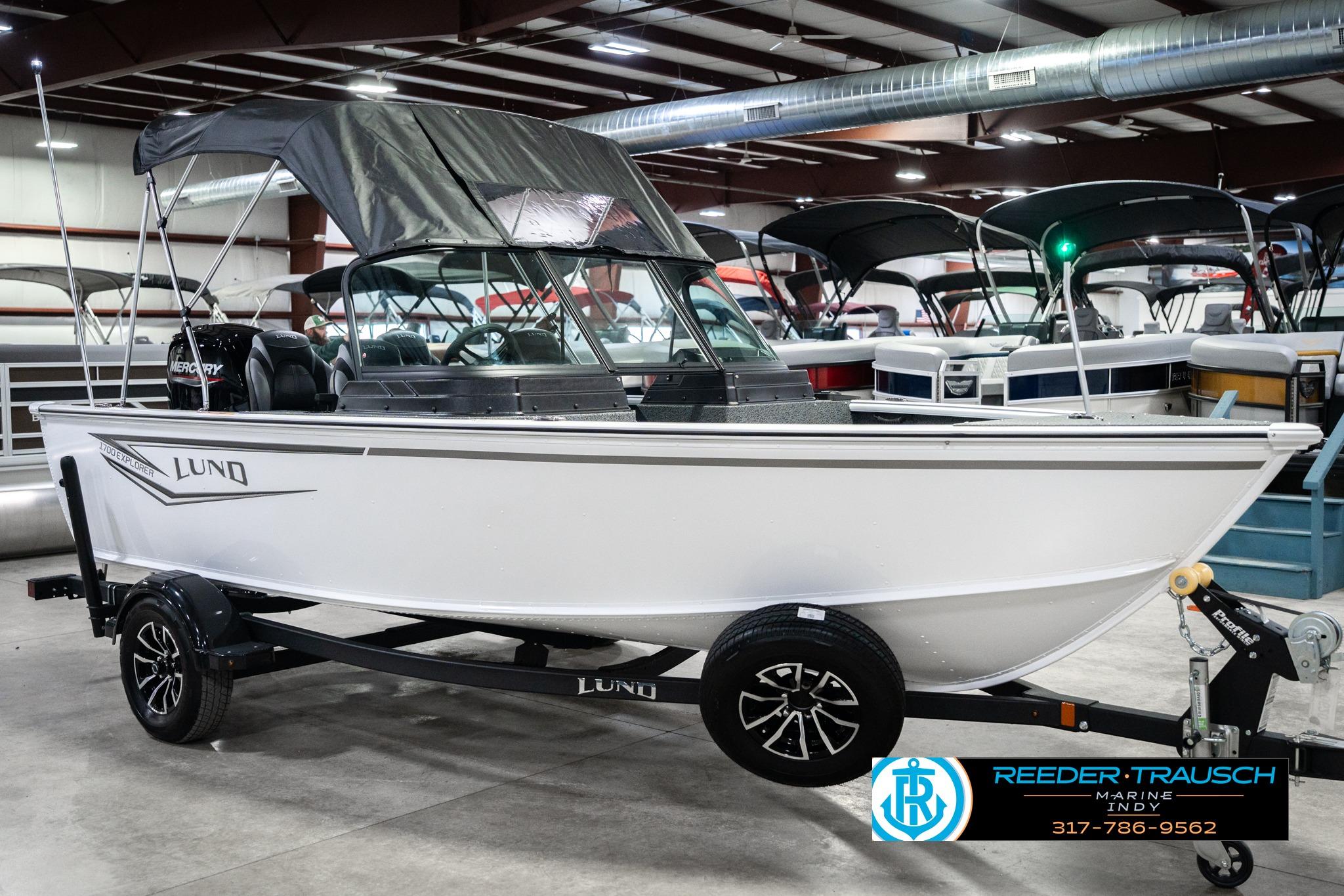 2026 Lund 1700 Explorer Sport boat on trailer in showroom, featuring sleek design and canopy.