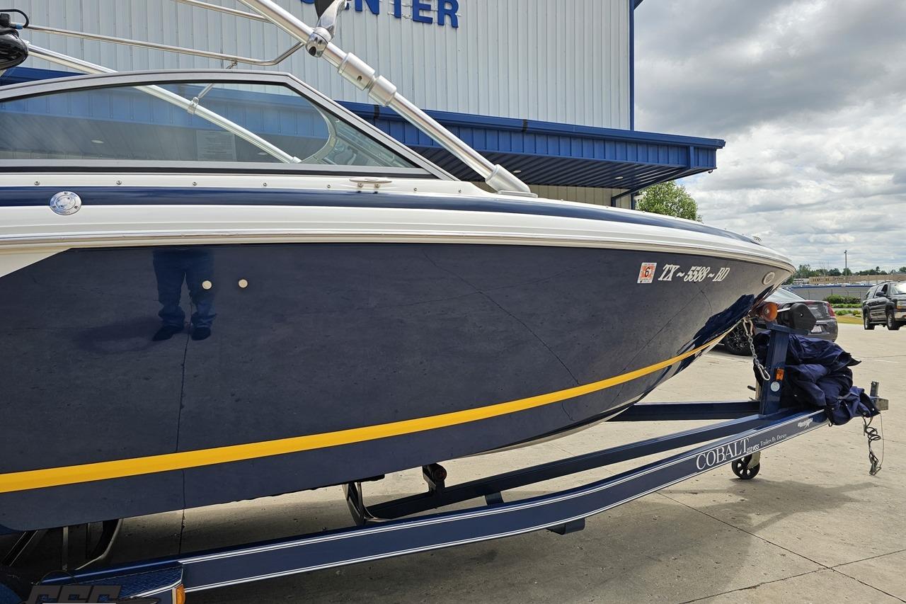 2010 Cobalt 232 WSS boat on trailer, parked outside a building under cloudy skies.