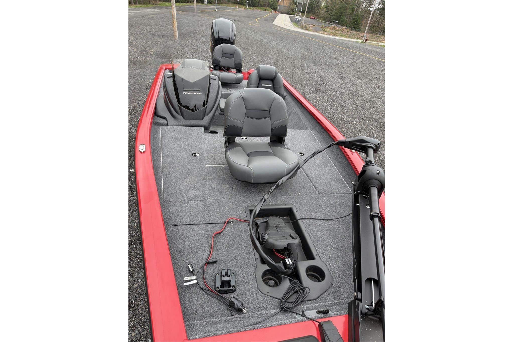 2026 Tracker Pro Team 175 boat with gray seating and red trim, parked on asphalt.