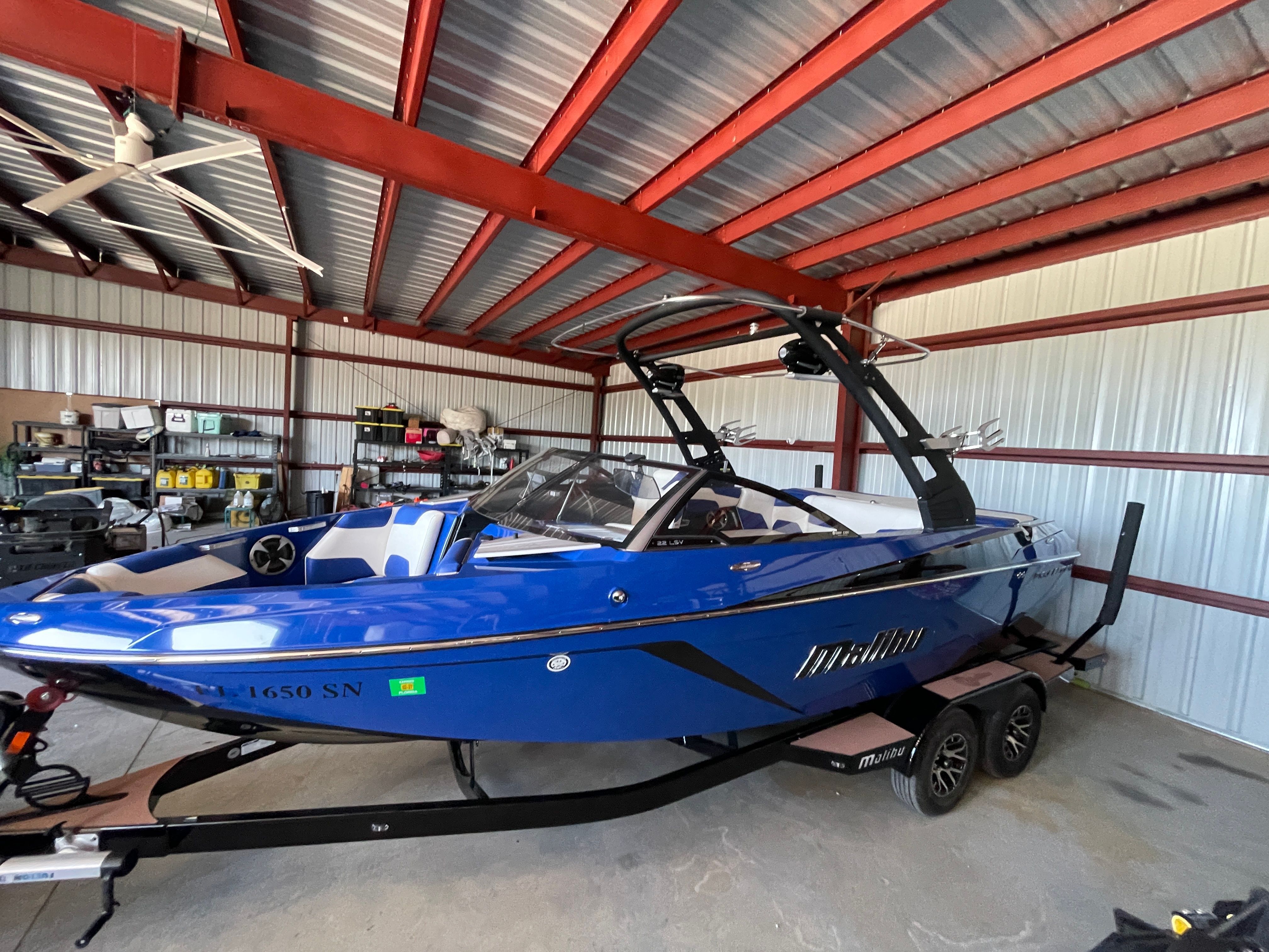 A blue 2019 Malibu Wakesetter 22 LSV sits on a trailer in a warehouse.