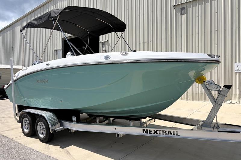 2026 Hurricane SunDeck Sport 2050 OB boat on trailer, parked near a building.
