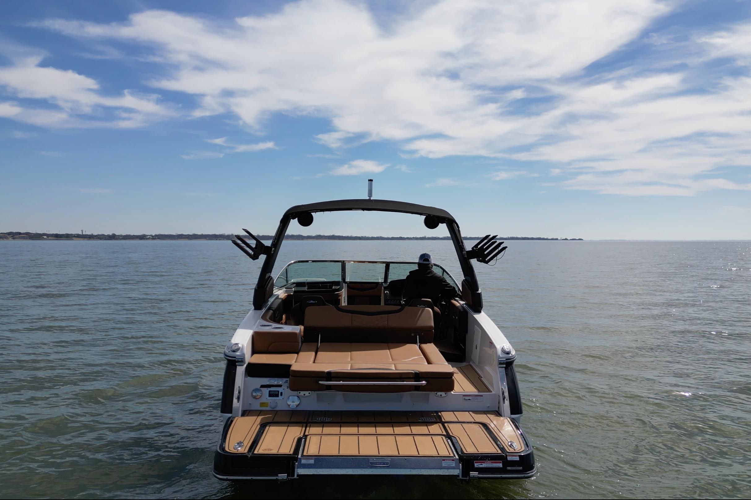 2023 Chaparral 26 Surf boat on calm water under a blue sky.
