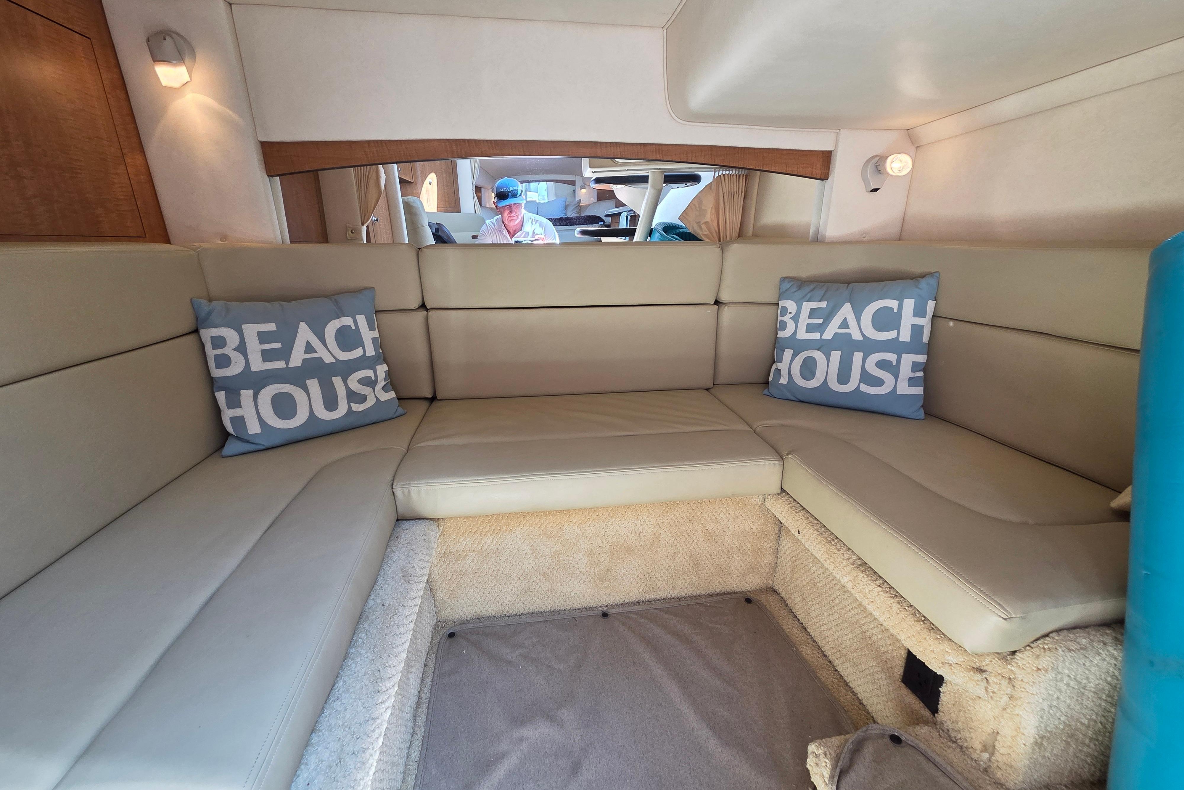 Interior of 2006 Sea Ray Sundancer 320 with beige seating and "Beach House" pillows.