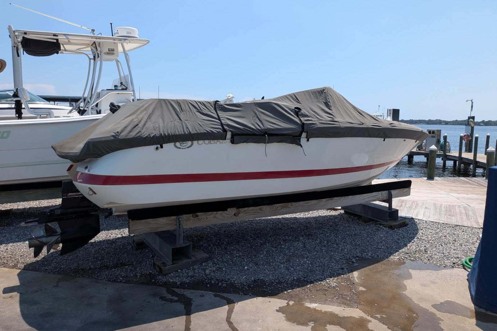 Covered 2020 Cobalt 206 boat on a dock, near water and other boats.