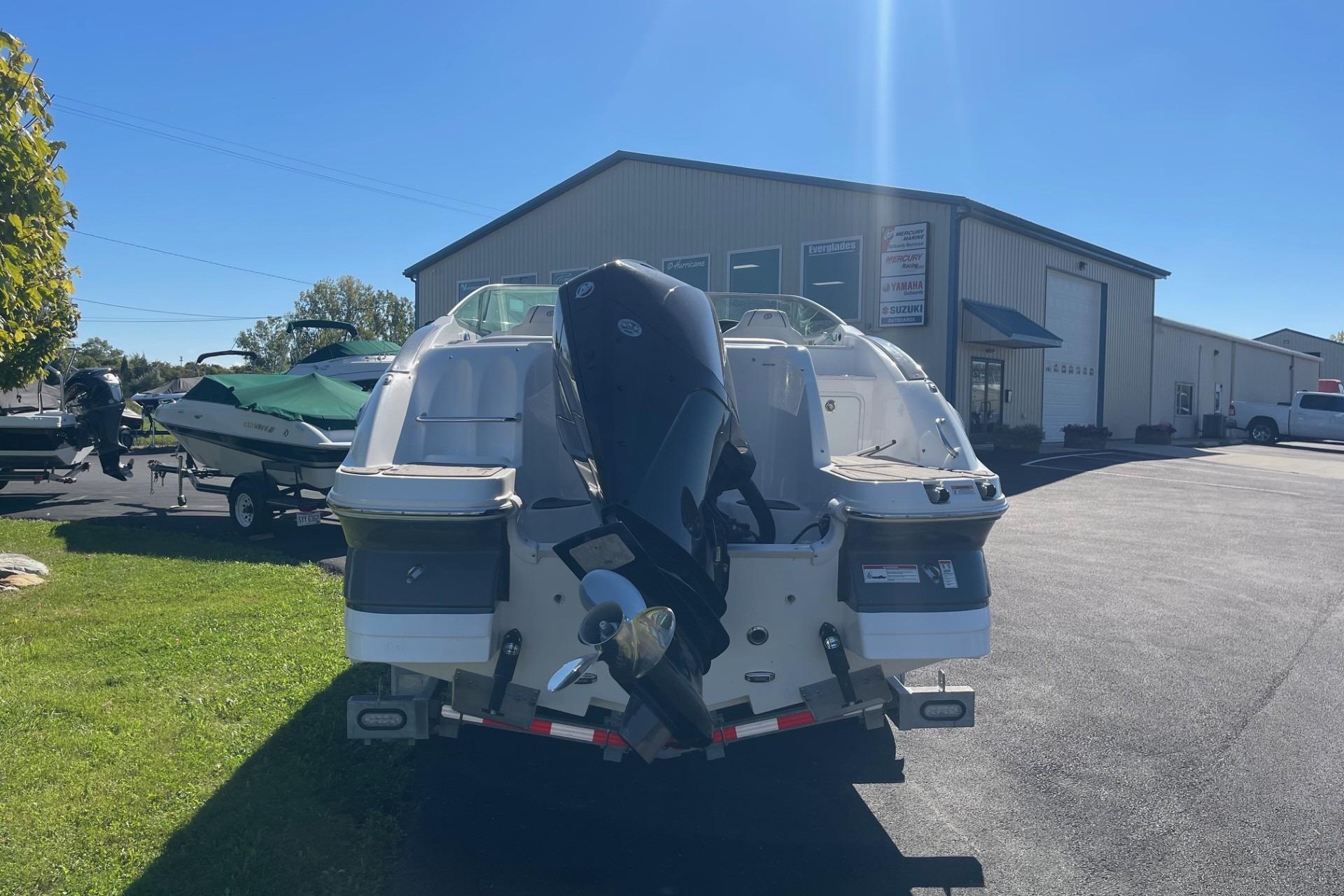 2023 Hurricane SunDeck 2400 OB boat with outboard motor in a dealership lot.