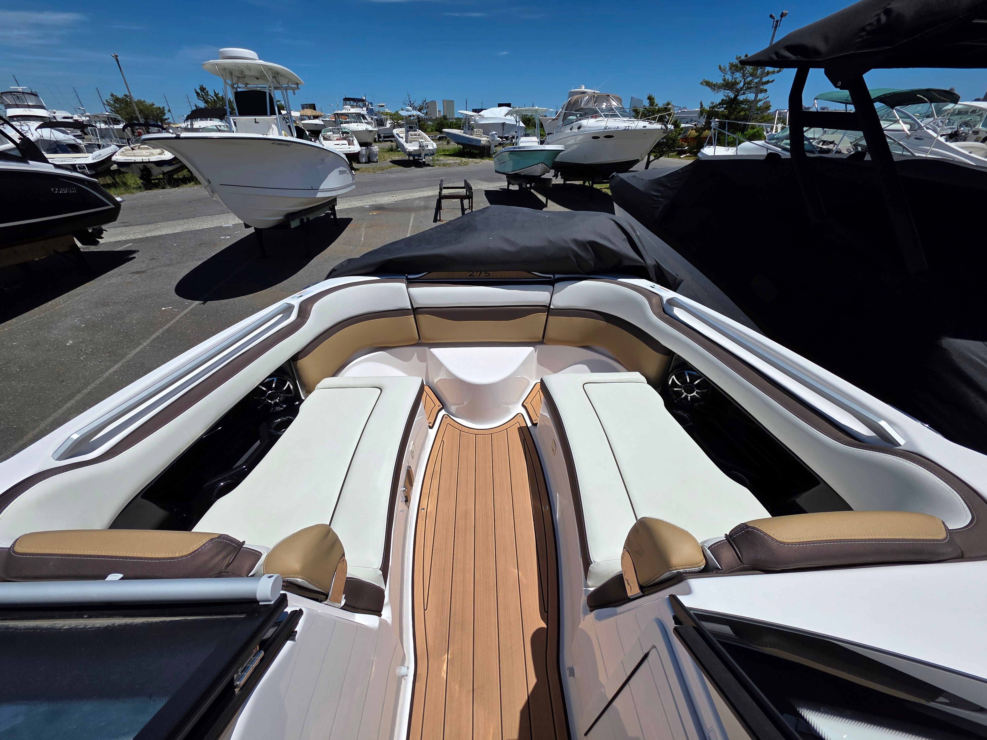 The image shows the cockpit of a 2023 Yamaha Boats sd275 with sleek seating and wooden flooring.