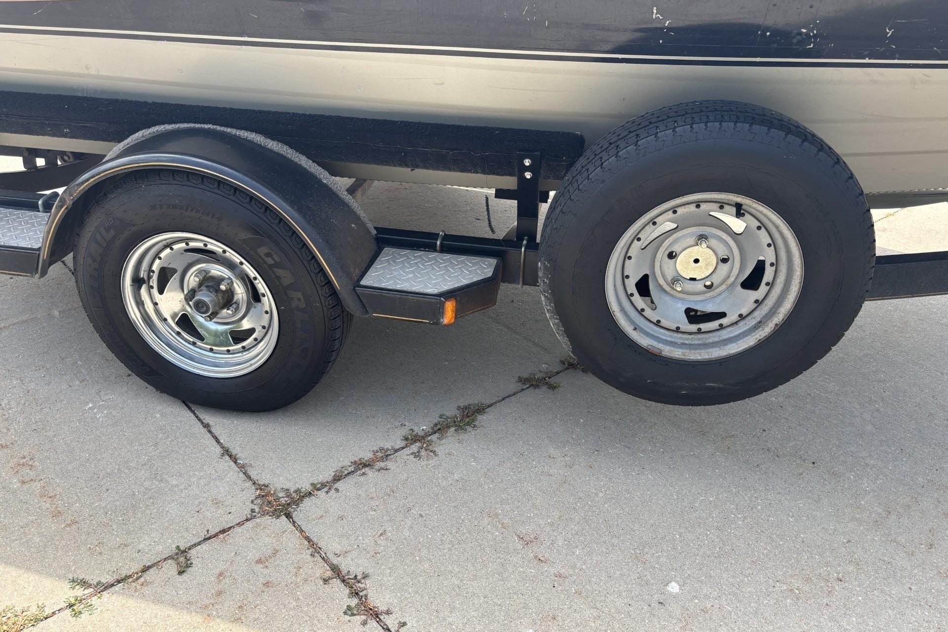 Trailer wheels of a 1999 Tracker Targa 18 boat on concrete pavement.