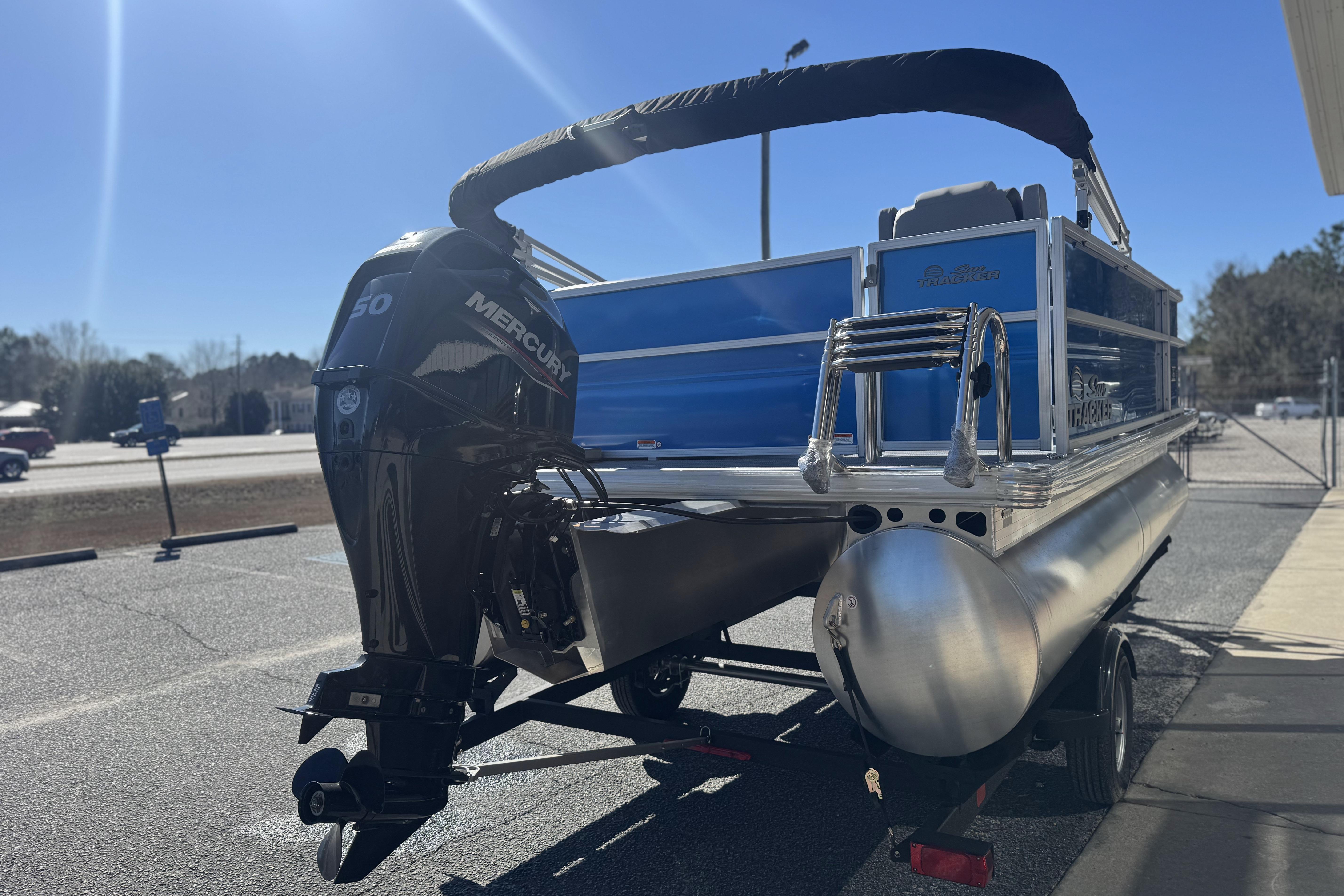 2026 Sun Tracker Party Barge 16 DLX pontoon boat with Mercury engine in parking lot.