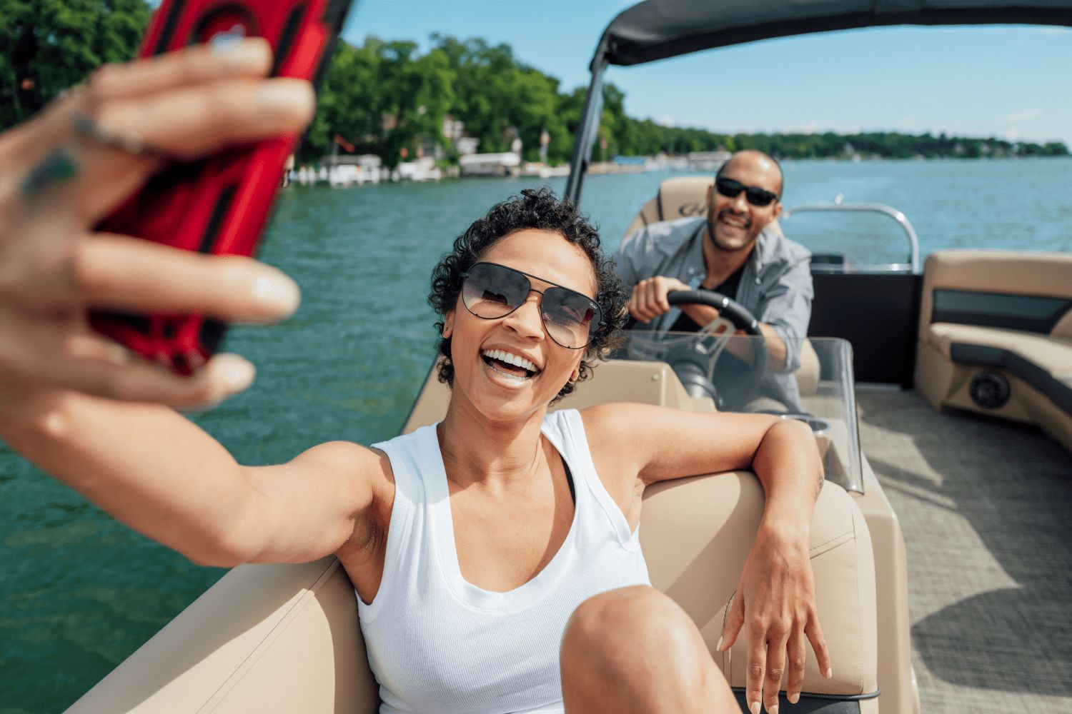 A couple enjoys a boat ride on a Harris Cruiser 230 on a calm lake.