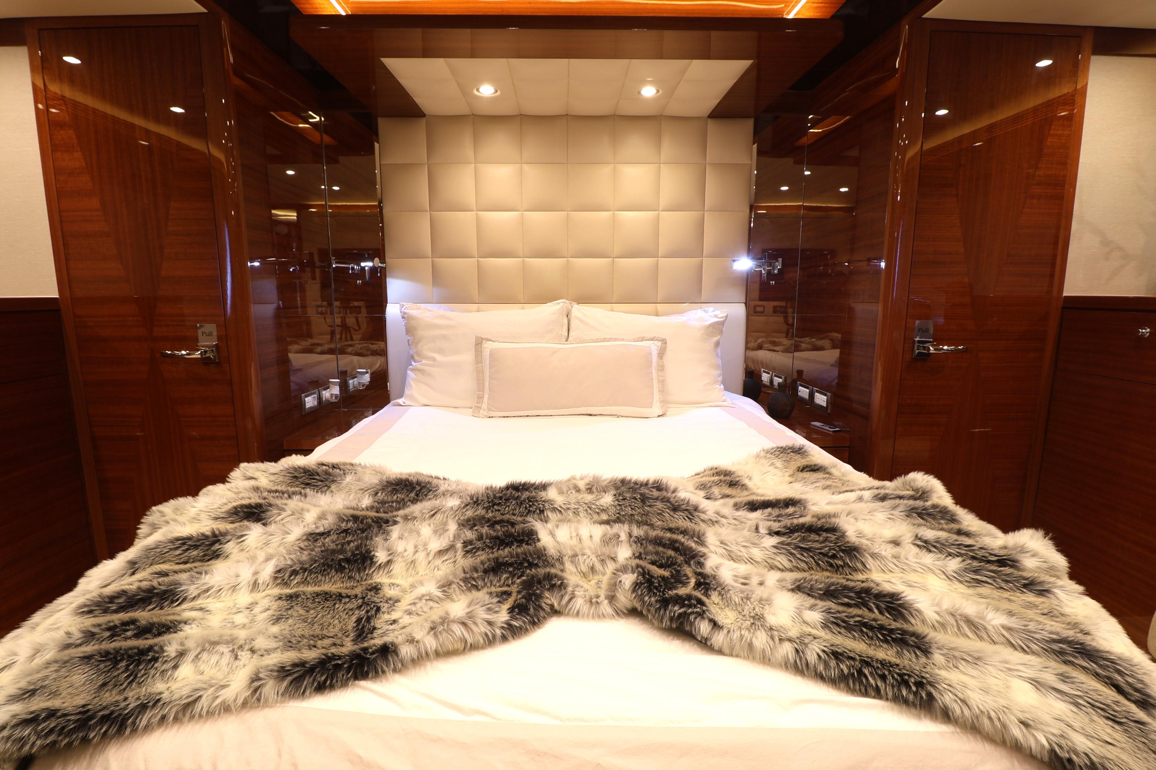 Luxurious bedroom interior on 2013 Cheoy Lee Bravo yacht with plush bedding and elegant wood finishes.