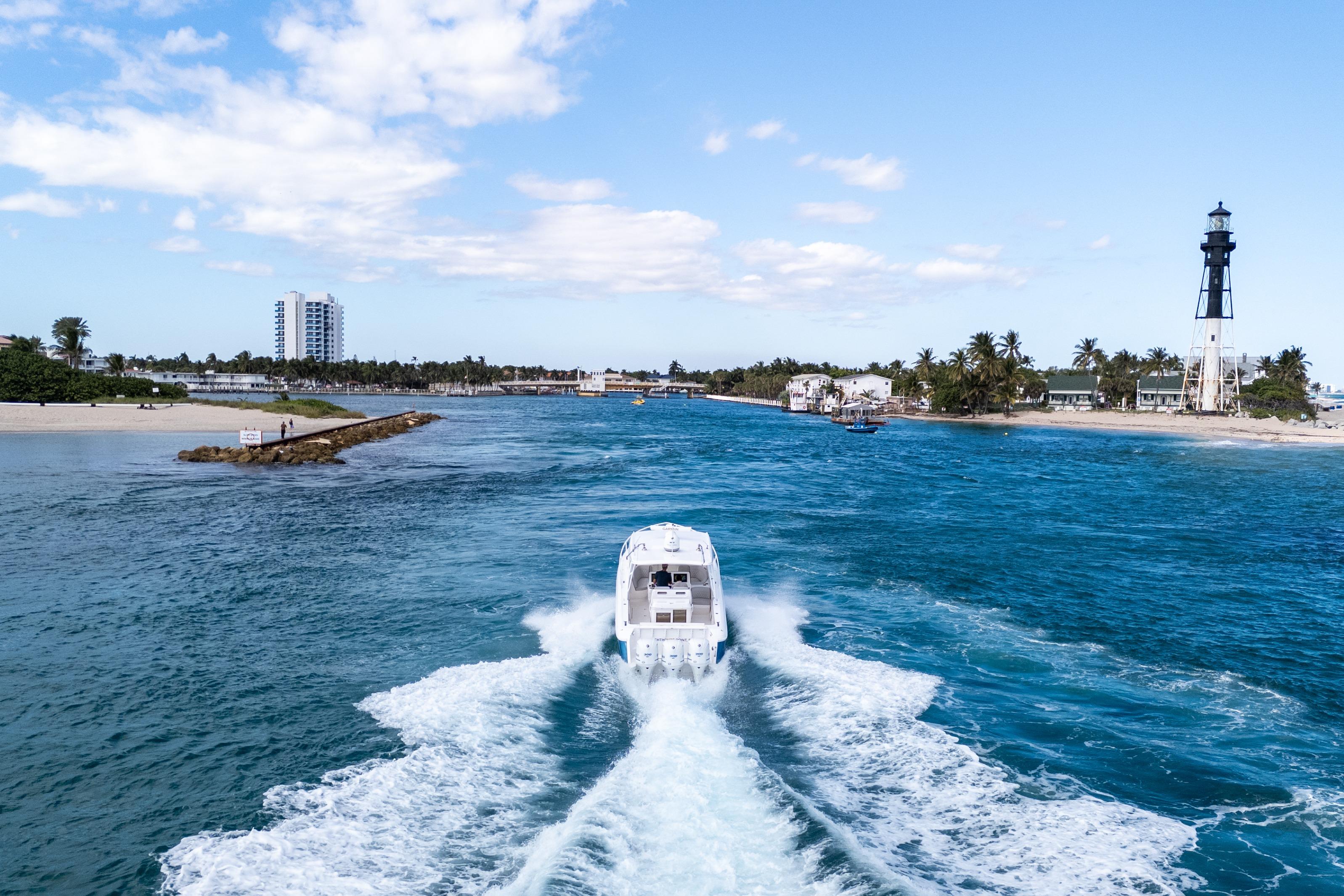 2019 Intrepid 407 Cuddy cruising near a lighthouse on a sunny day.