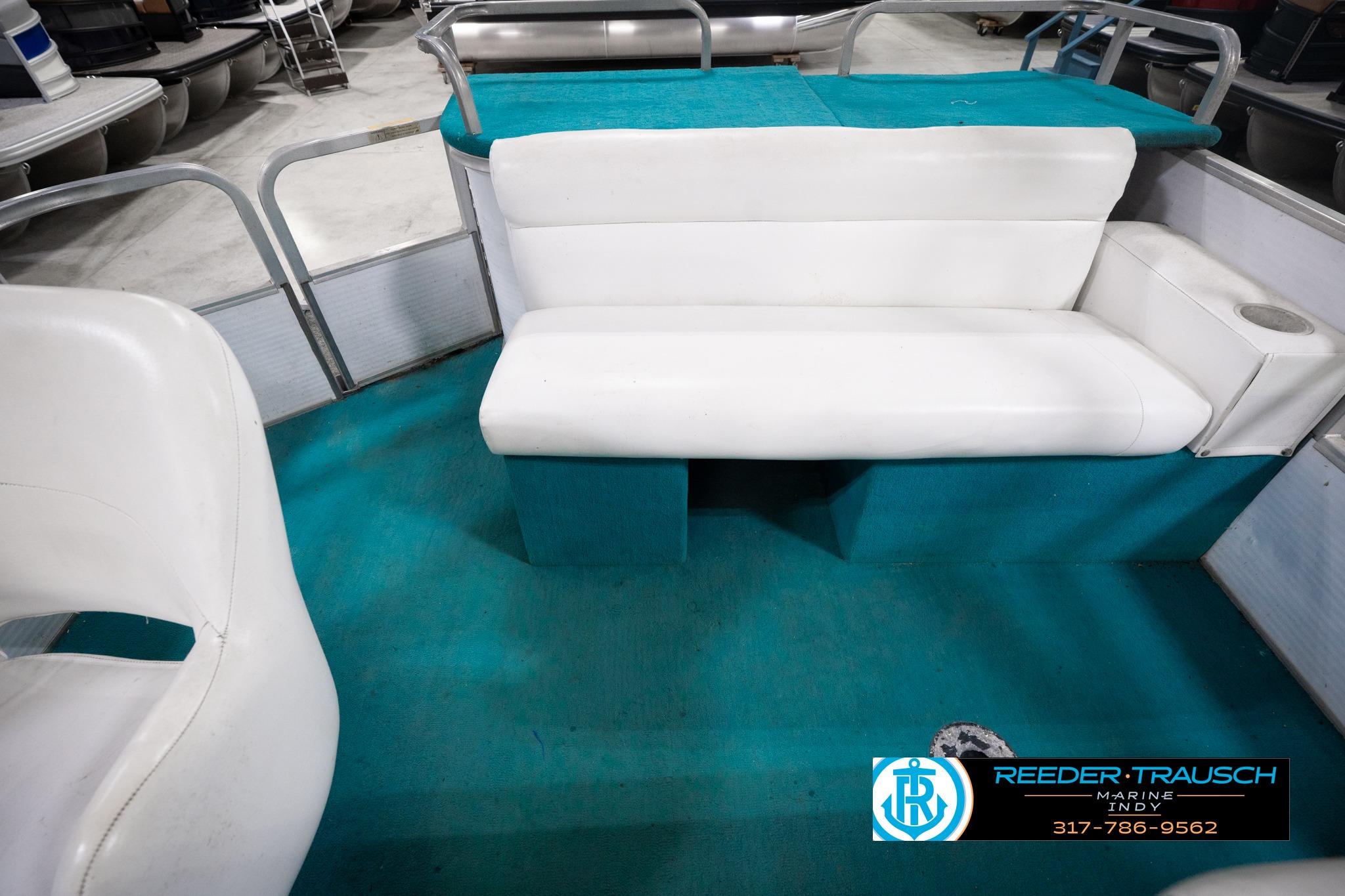 Interior of a 1992 Godfrey Sweetwater boat with white seating and teal flooring.