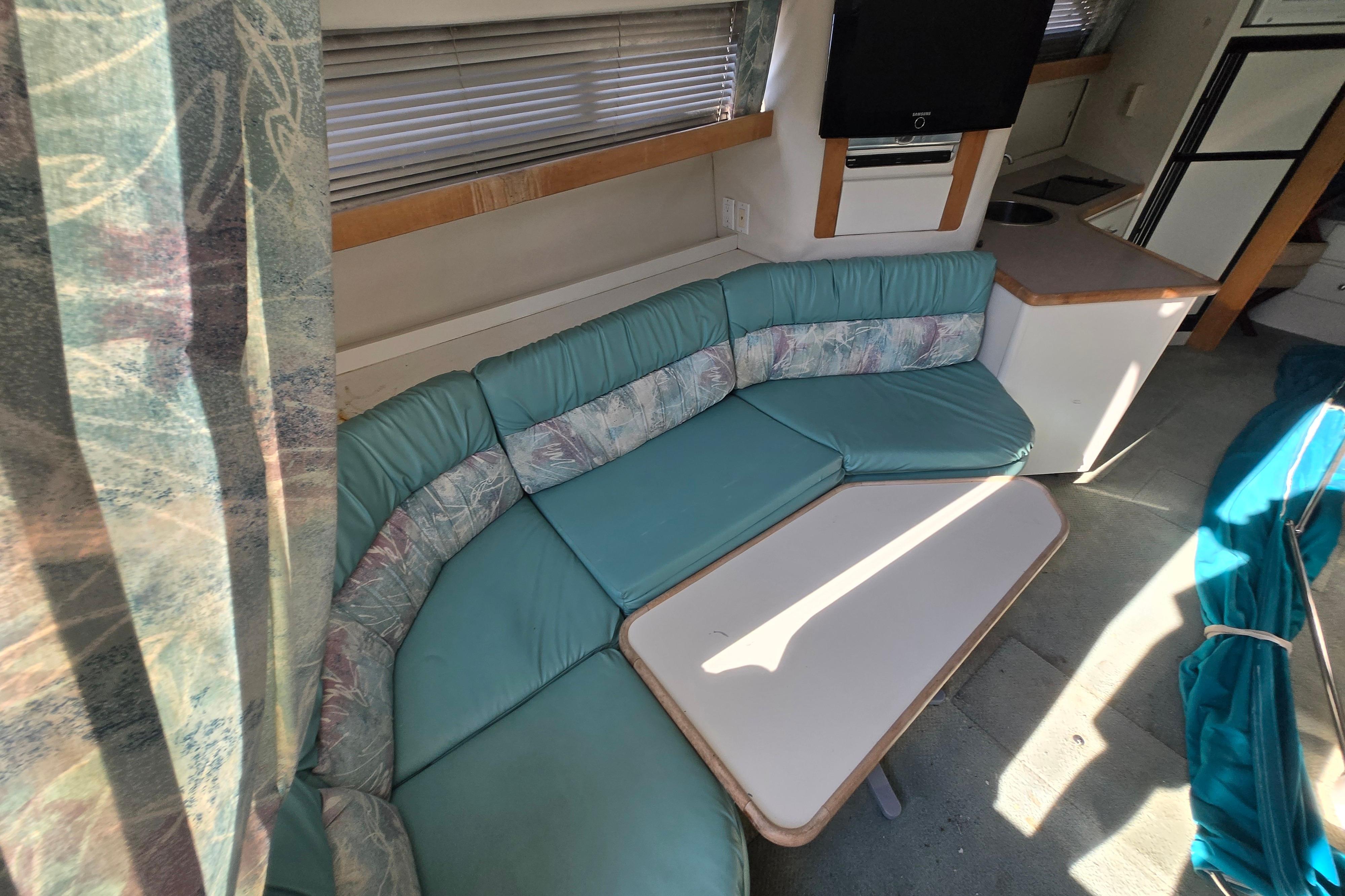 Interior of a 1994 Carver 380 Santego yacht with teal seating and a compact table.
