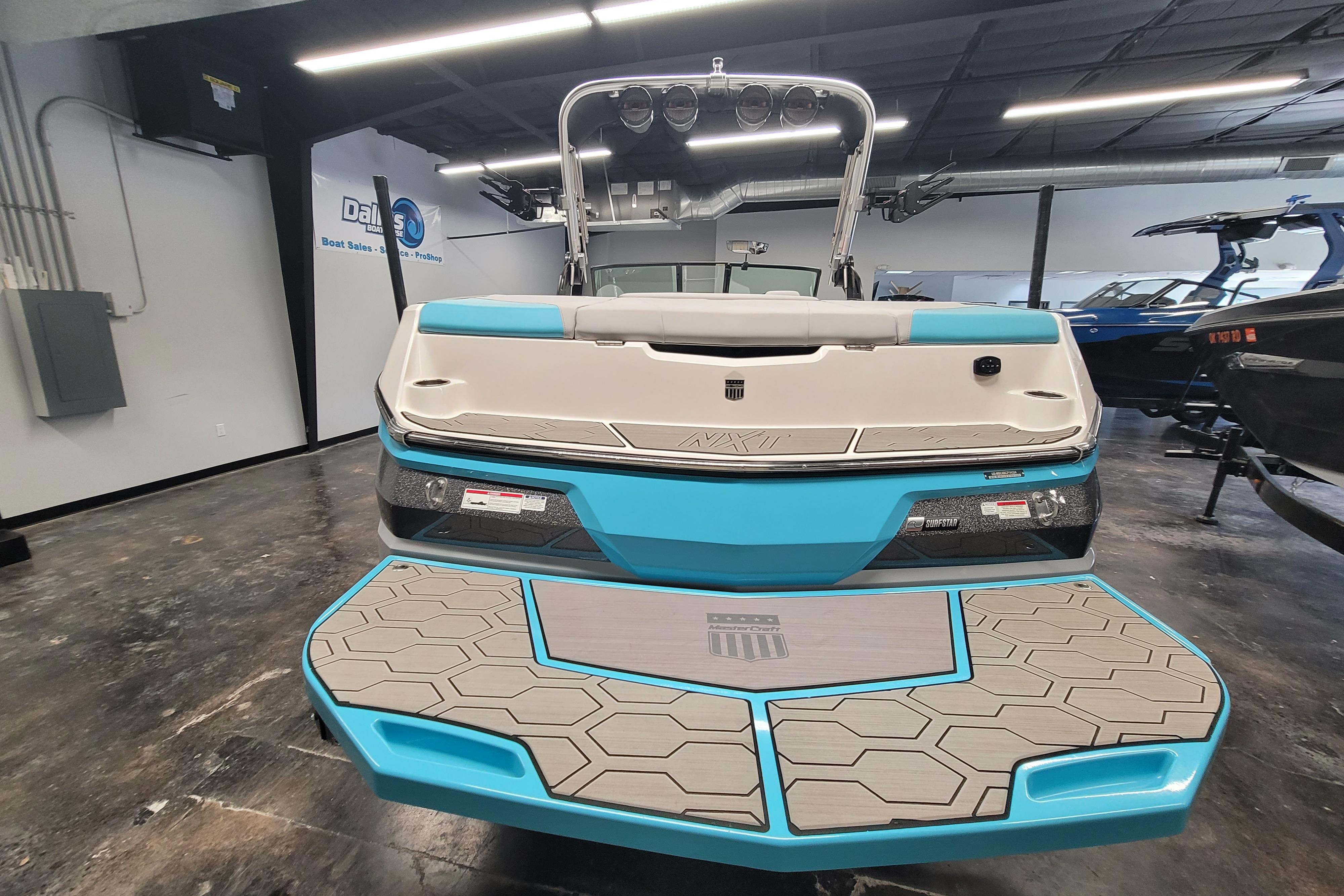 2024 MasterCraft NXT24 boat in showroom, featuring sleek design and vibrant blue accents.