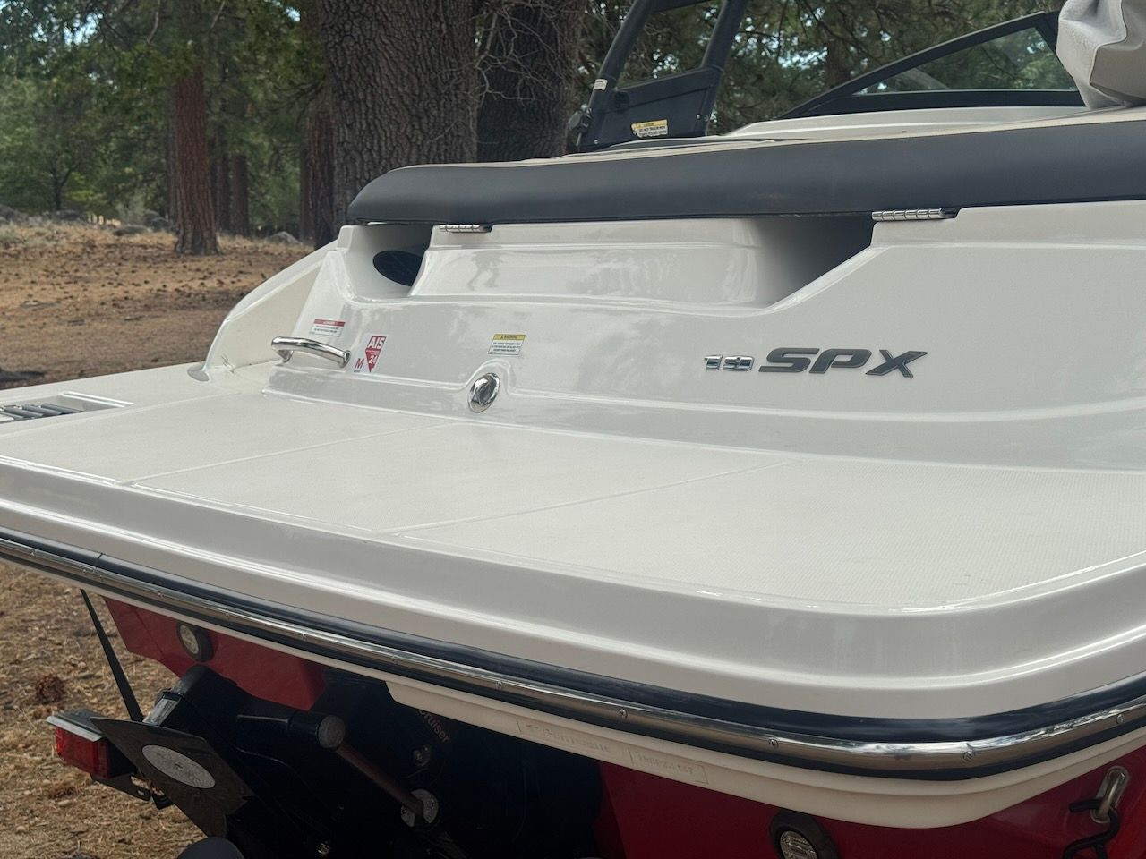 Rear view of a 2016 Sea Ray SPX 190 Outboard, parked in a wooded area.